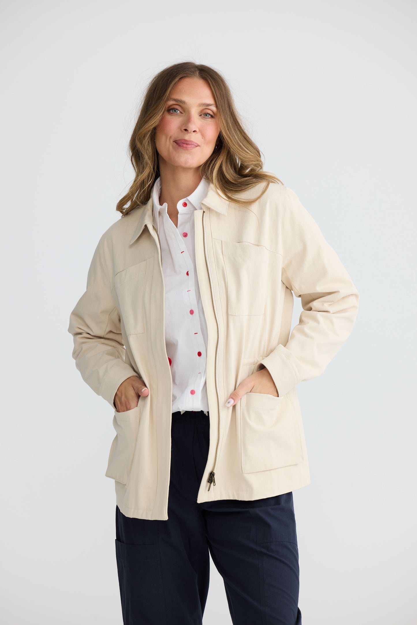 Model wearing Sabbia Jacket Cream with concealed zip and waist drawcord, alternate view on white background