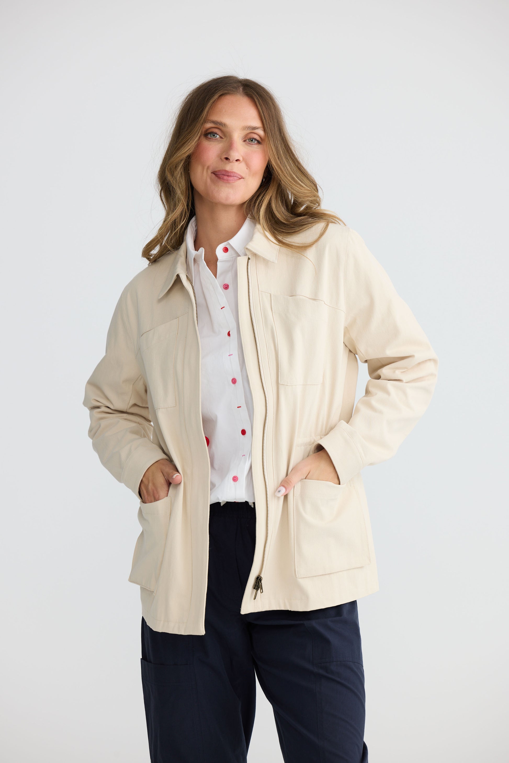 Model wearing Sabbia Jacket Cream with concealed zip and waist drawcord, alternate view on white background