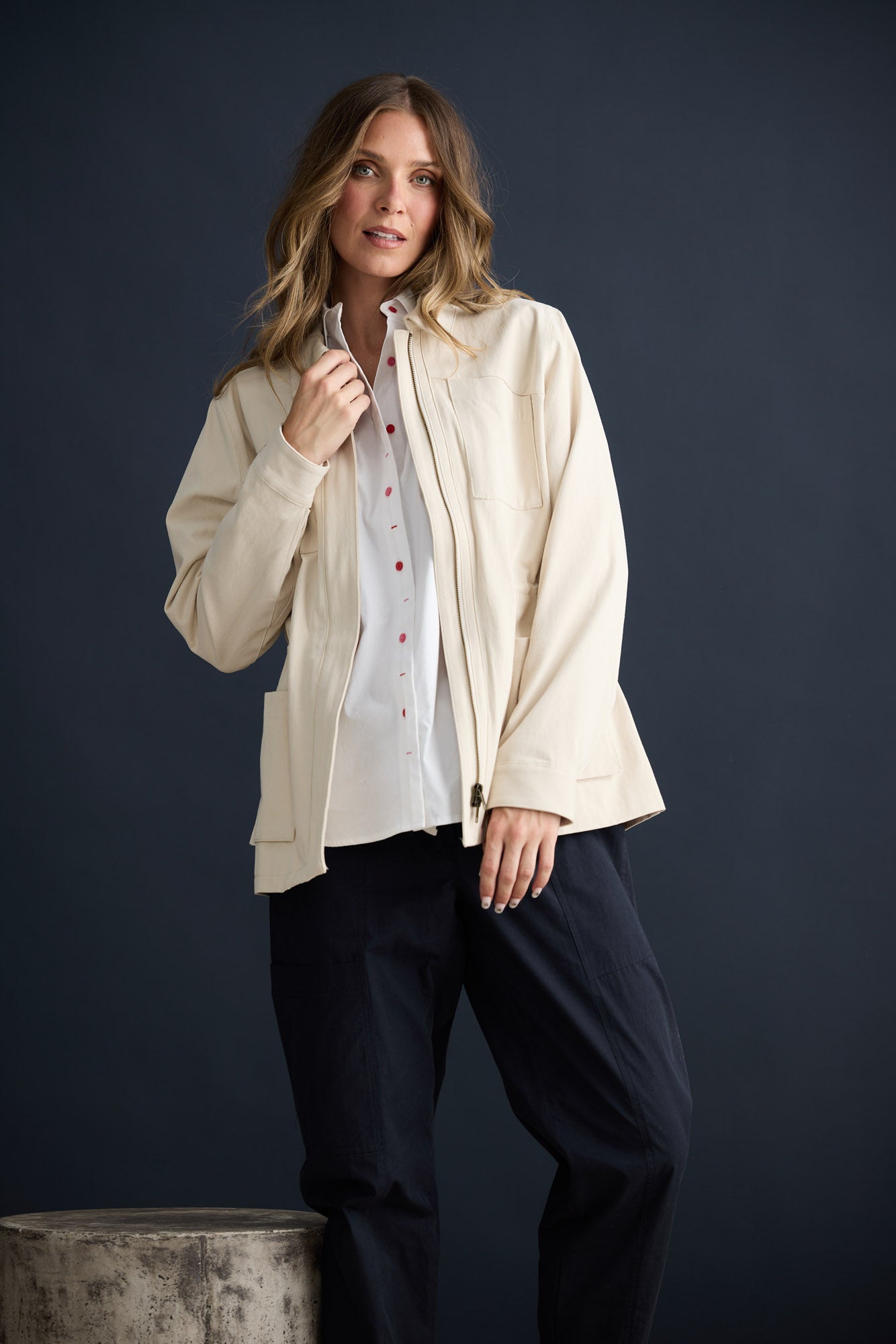 Model wearing Sabbia Jacket Cream with concealed zip and waist drawcord, campaign lifestyle view