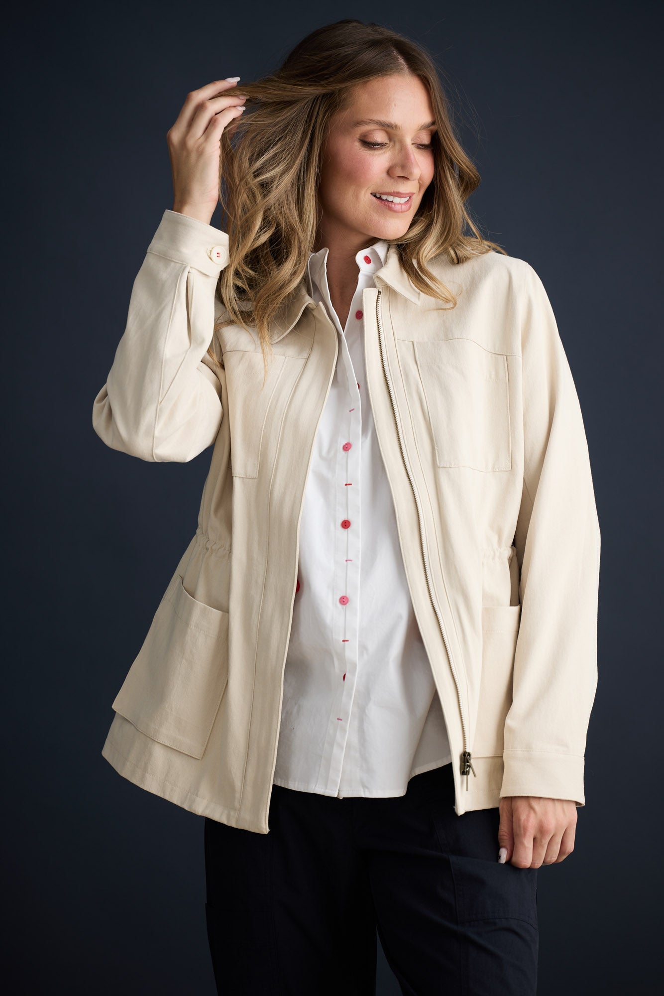 Model wearing Sabbia Jacket Cream with concealed zip and waist drawcord, campaign lifestyle view