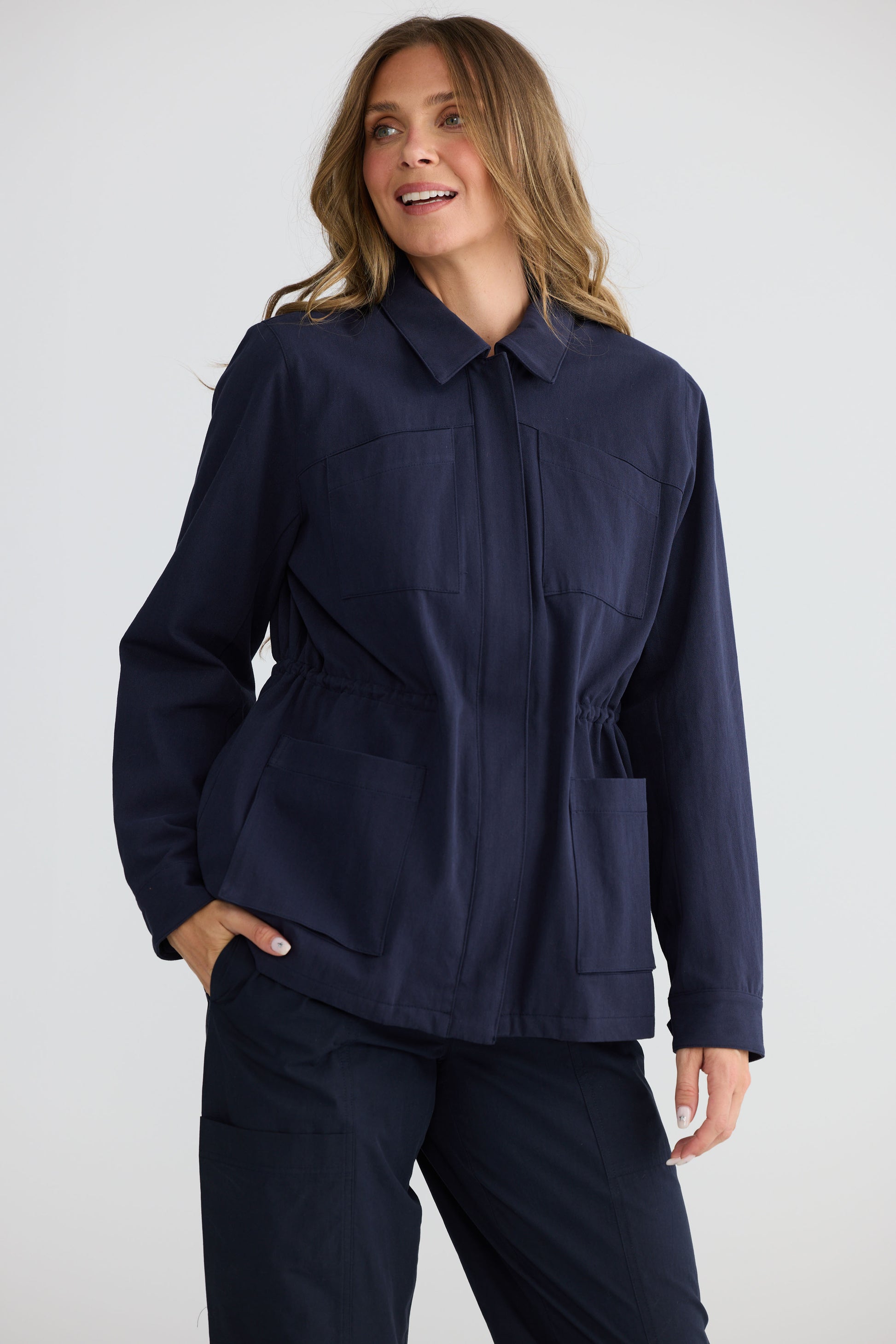 Model wearing Sabbia Jacket Navy with concealed zip and waist drawcord, front view on white background