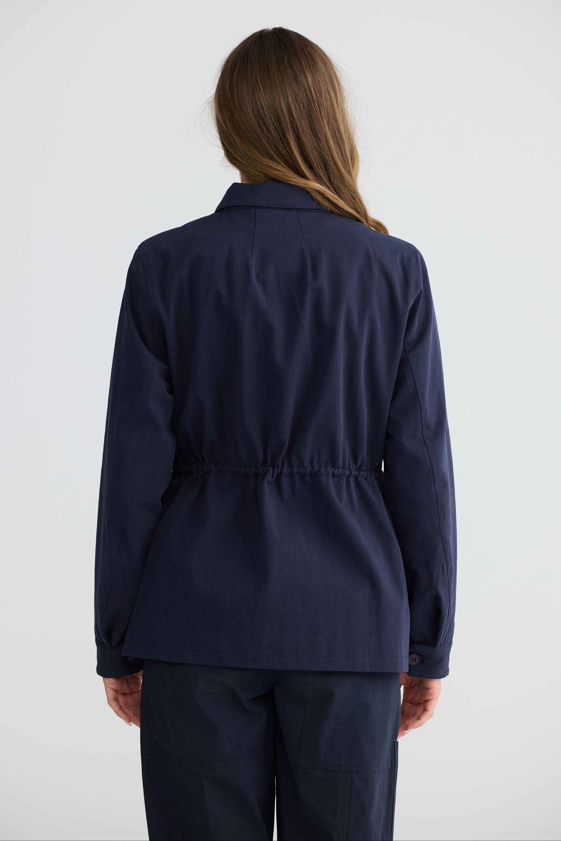 Model wearing Sabbia Jacket Navy with concealed zip and waist drawcord, full-length view on white background