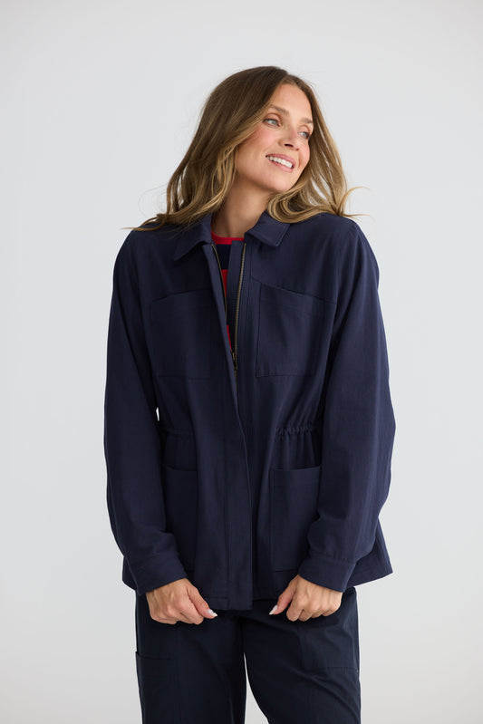 Model wearing Sabbia Jacket Navy with concealed zip and waist drawcord, alternate view on white background