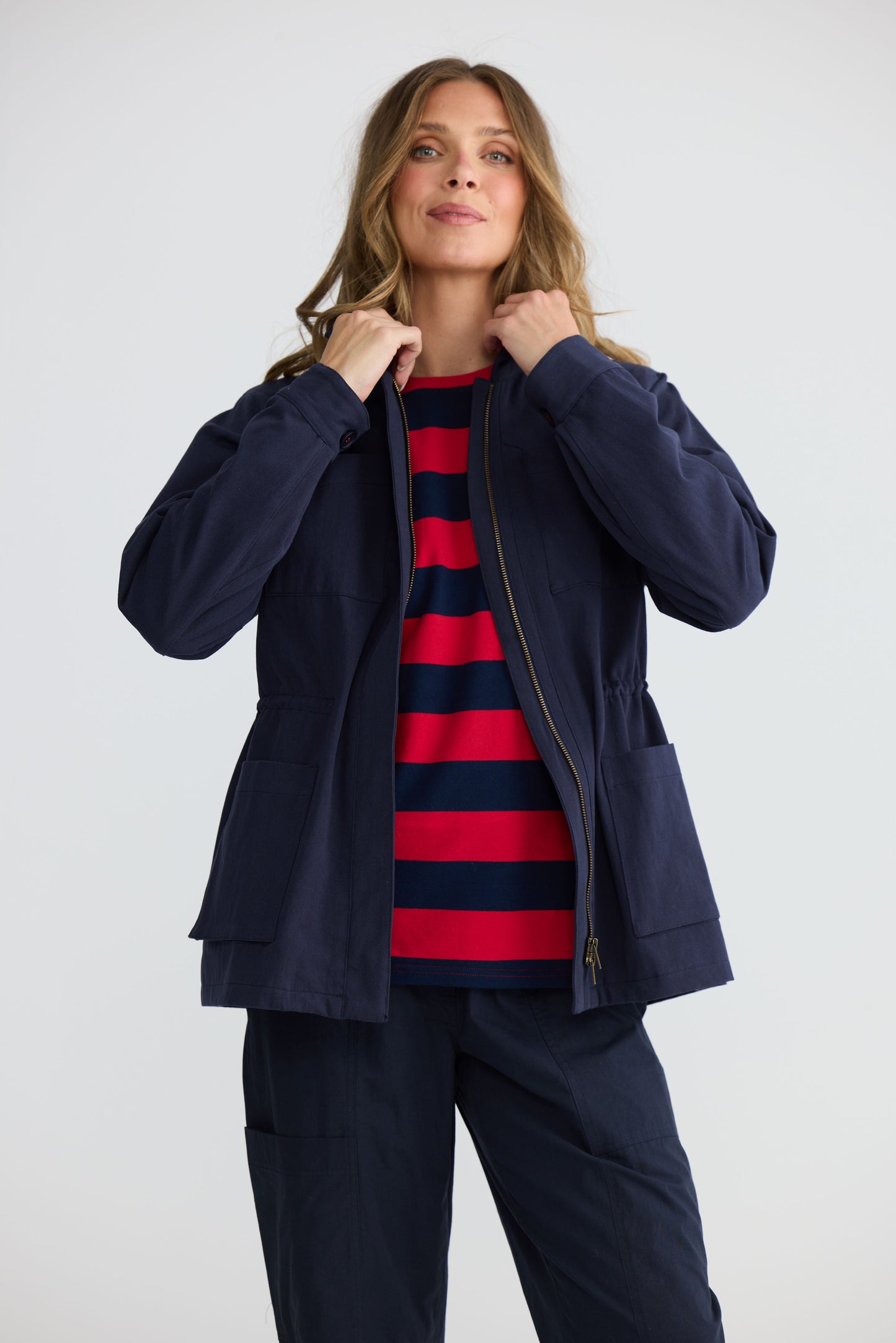 Model wearing Sabbia Jacket Navy with concealed zip and waist drawcord, back view on white background