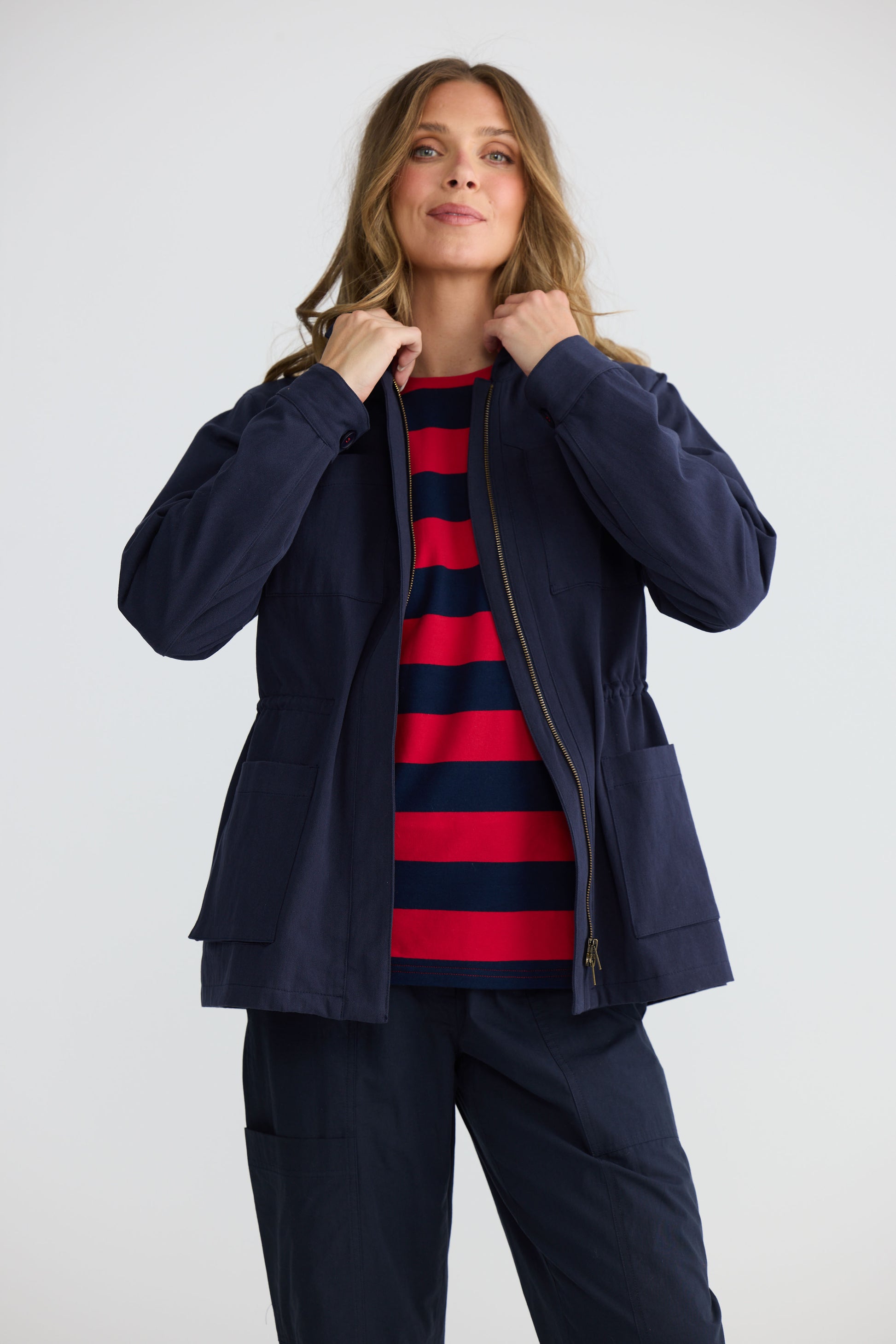 Model wearing Sabbia Jacket Navy with concealed zip and waist drawcord, back view on white background