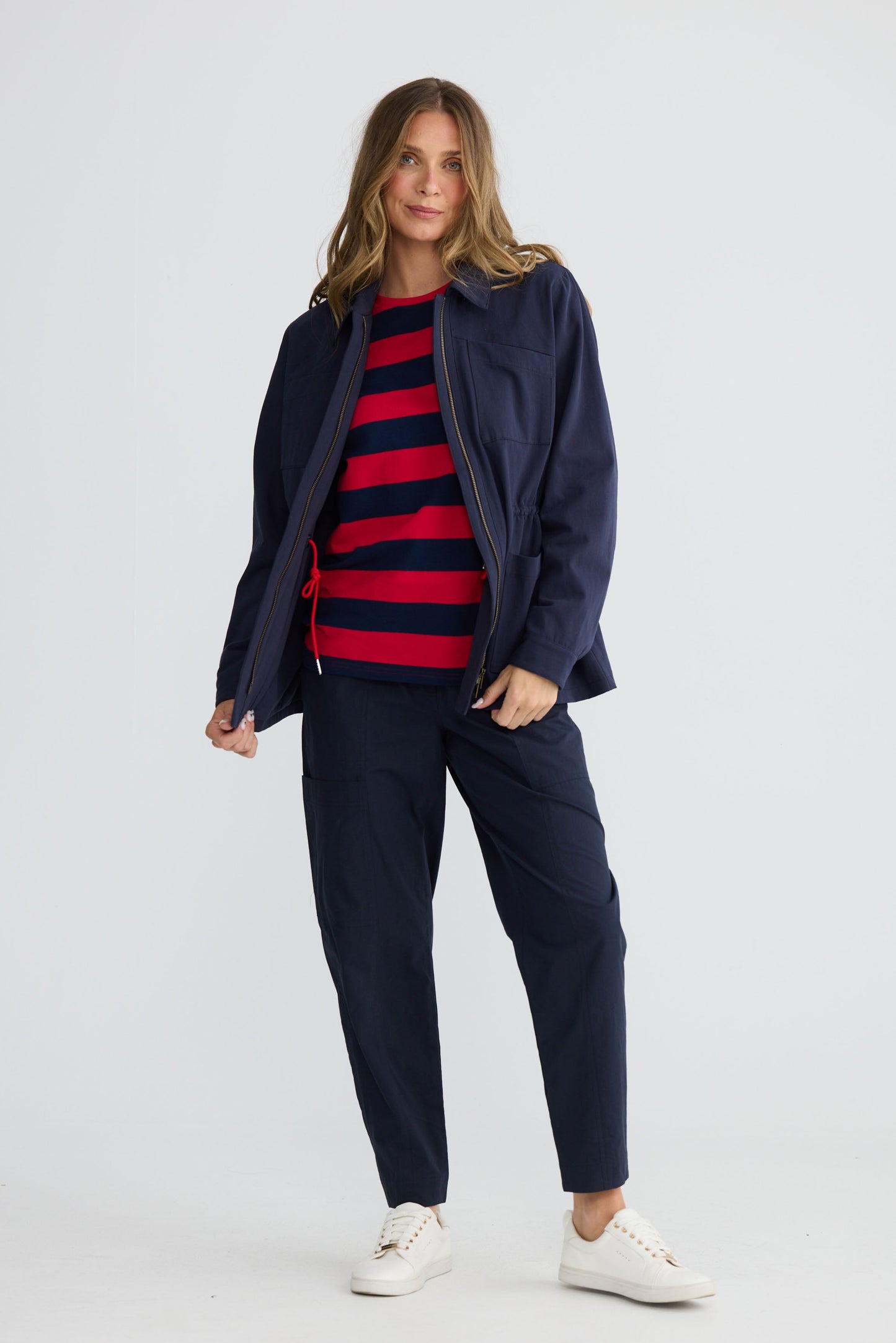 Model wearing Sabbia Jacket Navy with concealed zip and waist drawcord, side view on white background
