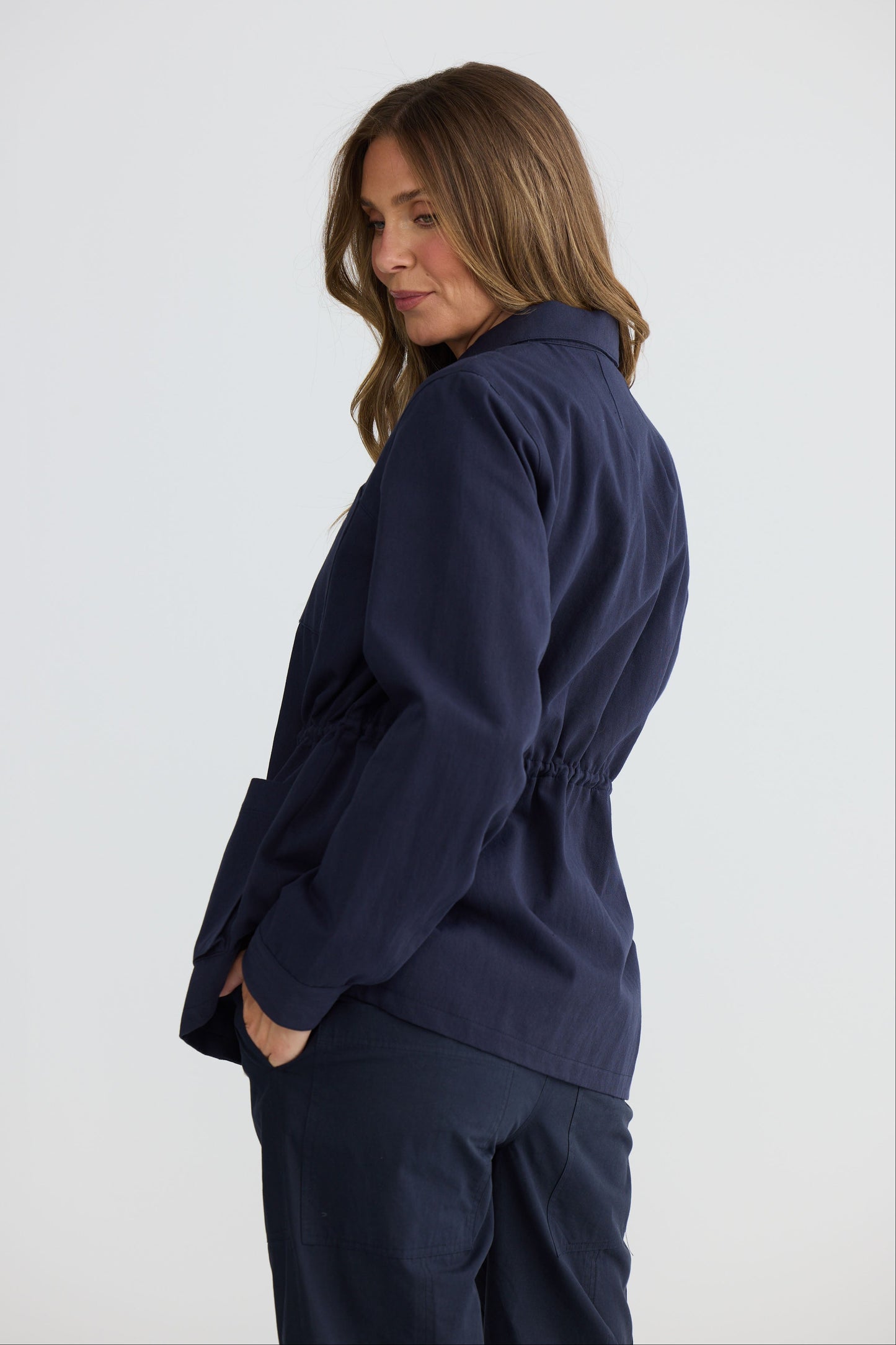 Model wearing Sabbia Jacket Navy with concealed zip and waist drawcord, detail view on white background