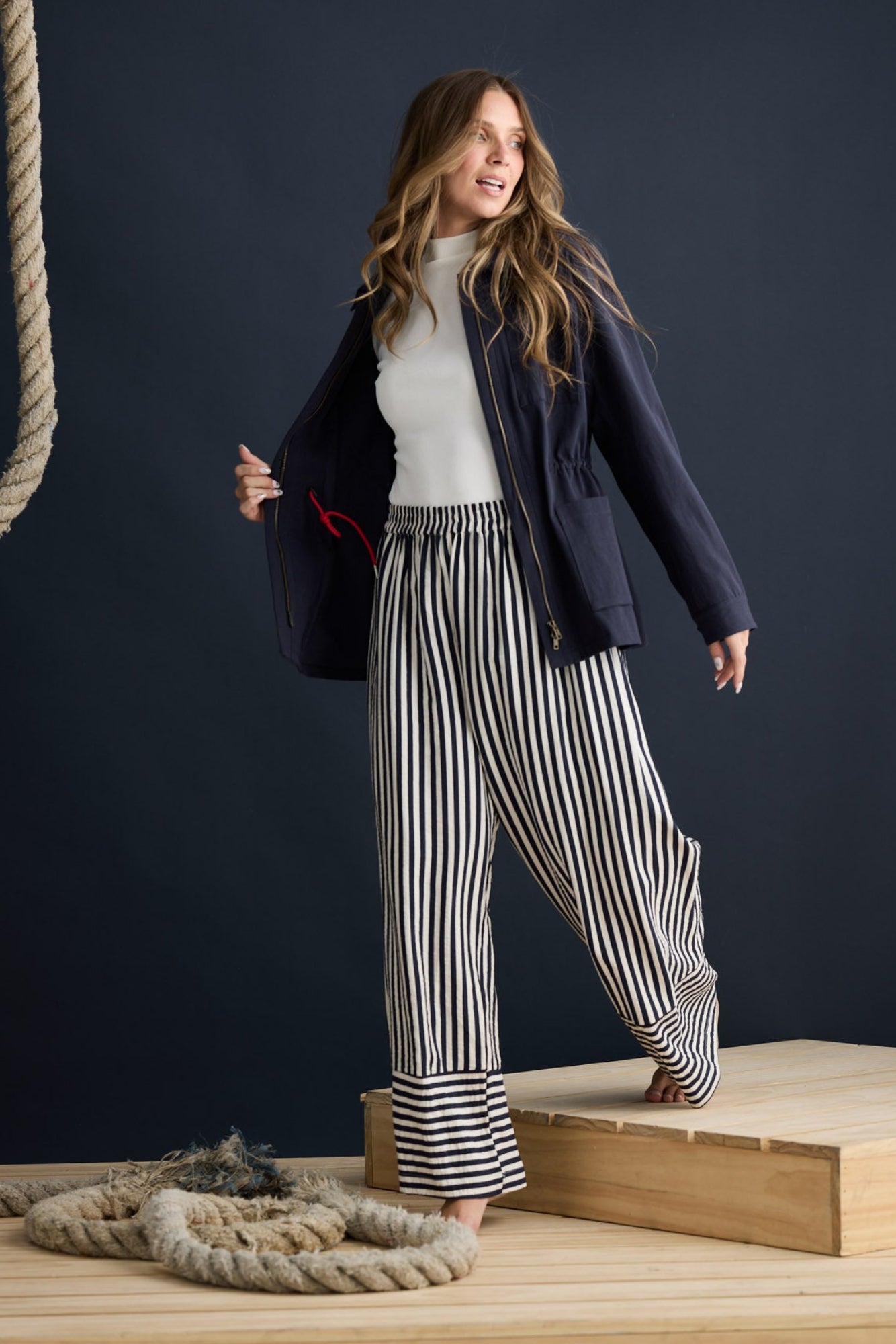 Model wearing Sabbia Jacket Navy with concealed zip and waist drawcord, campaign lifestyle view