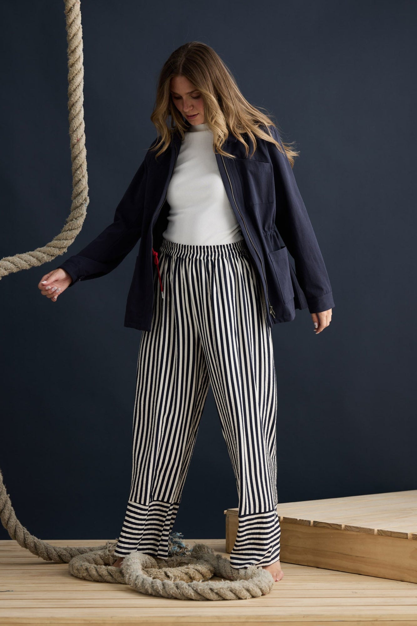 Model wearing Sabbia Jacket Navy with concealed zip and waist drawcord, campaign lifestyle view