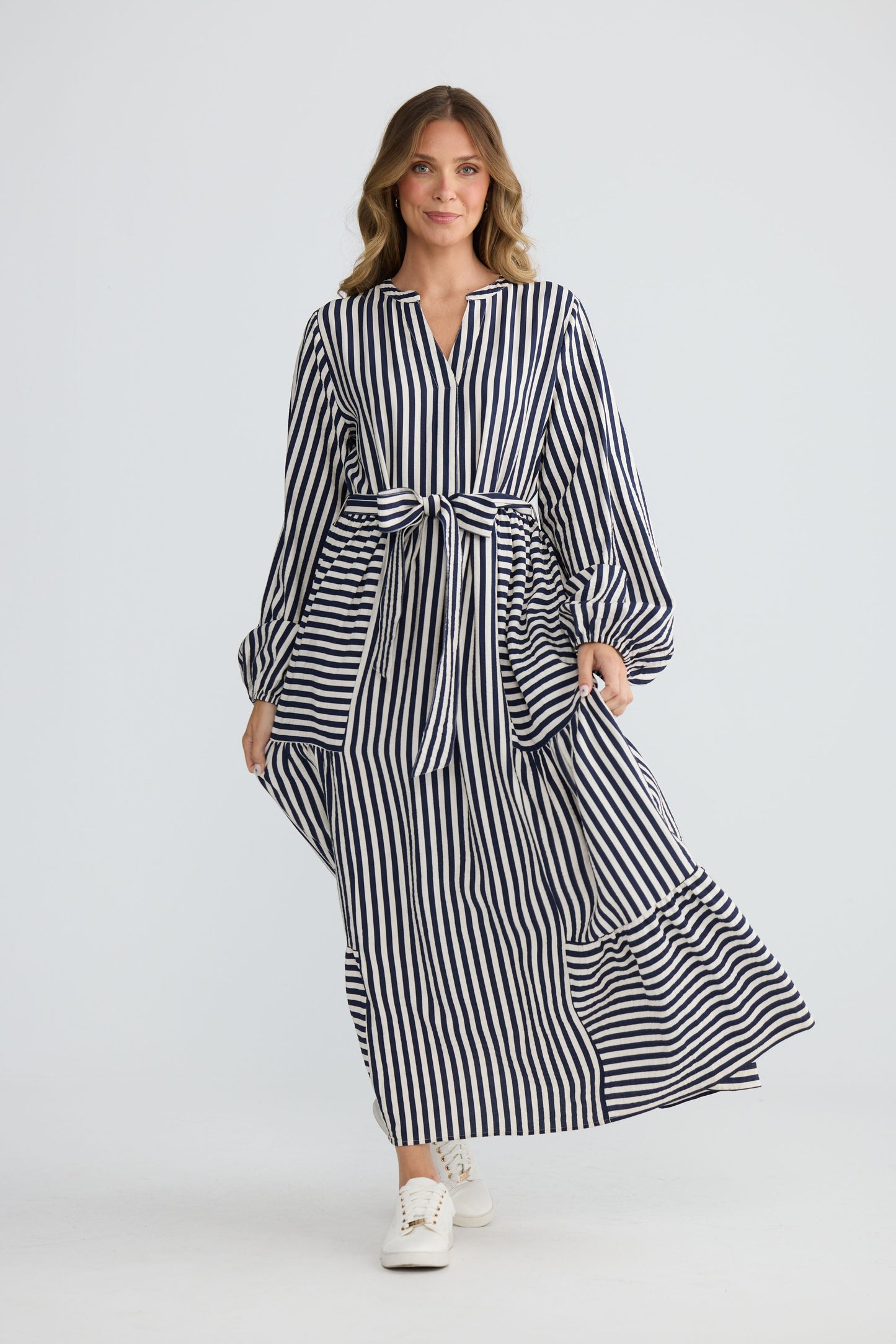 Model wearing Marla Dress Navy and White Stripe with balloon sleeves and waist tie, front view on white background