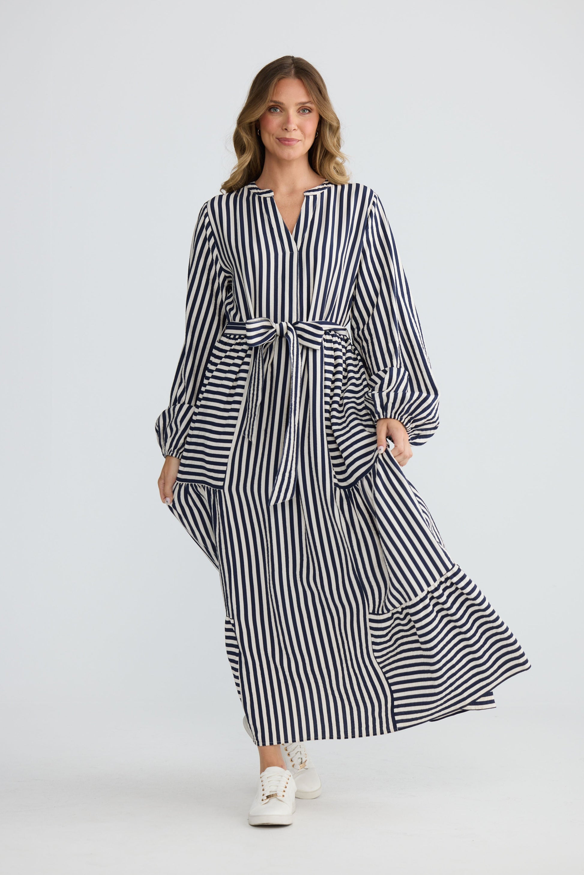 Model wearing Marla Dress Navy and White Stripe with balloon sleeves and waist tie, front view on white background