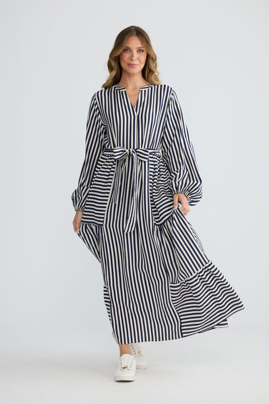 Model wearing Marla Dress Navy and White Stripe with balloon sleeves and waist tie, front view on white background