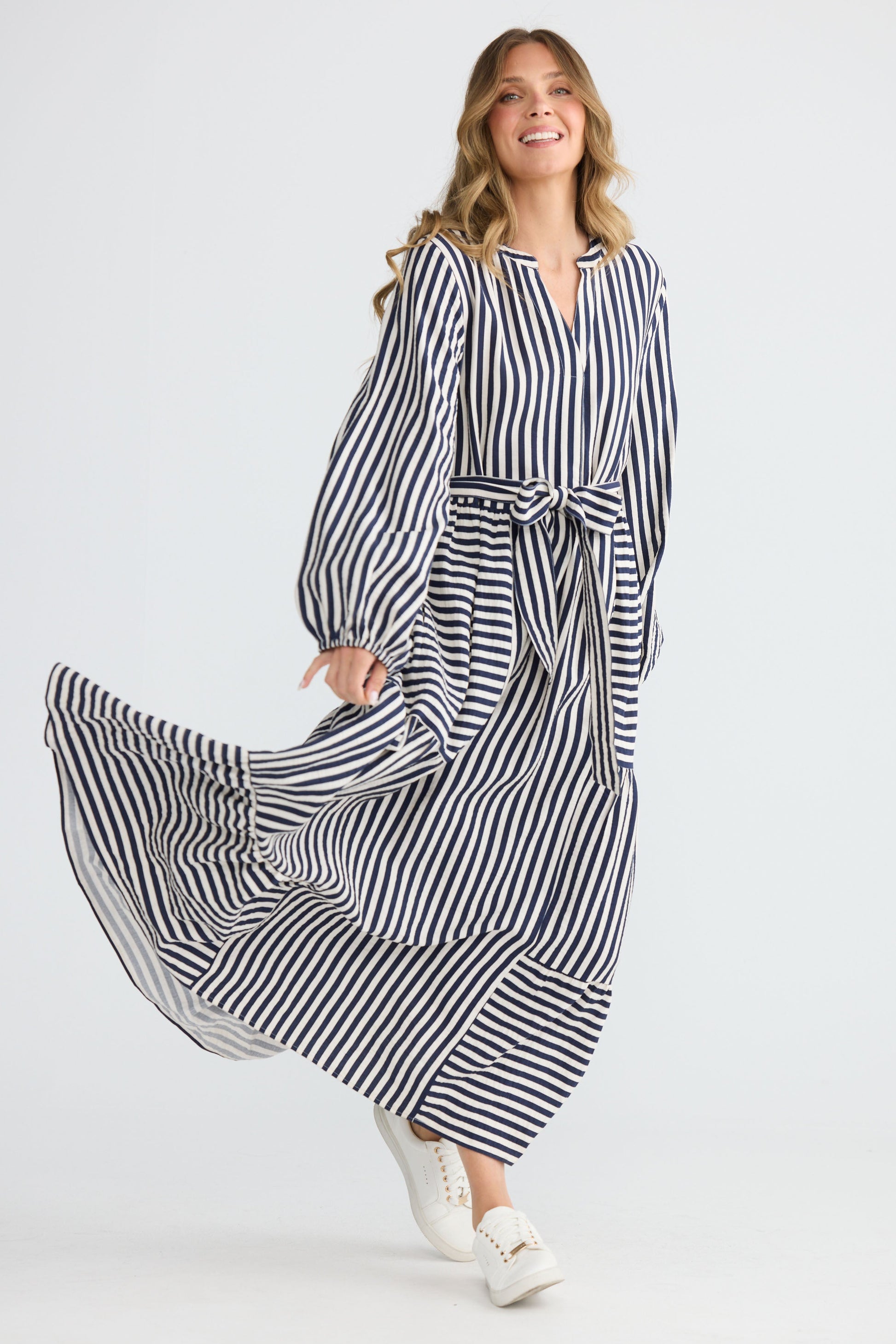 Model wearing Marla Dress Navy and White Stripe with balloon sleeves and waist tie, back view on white background