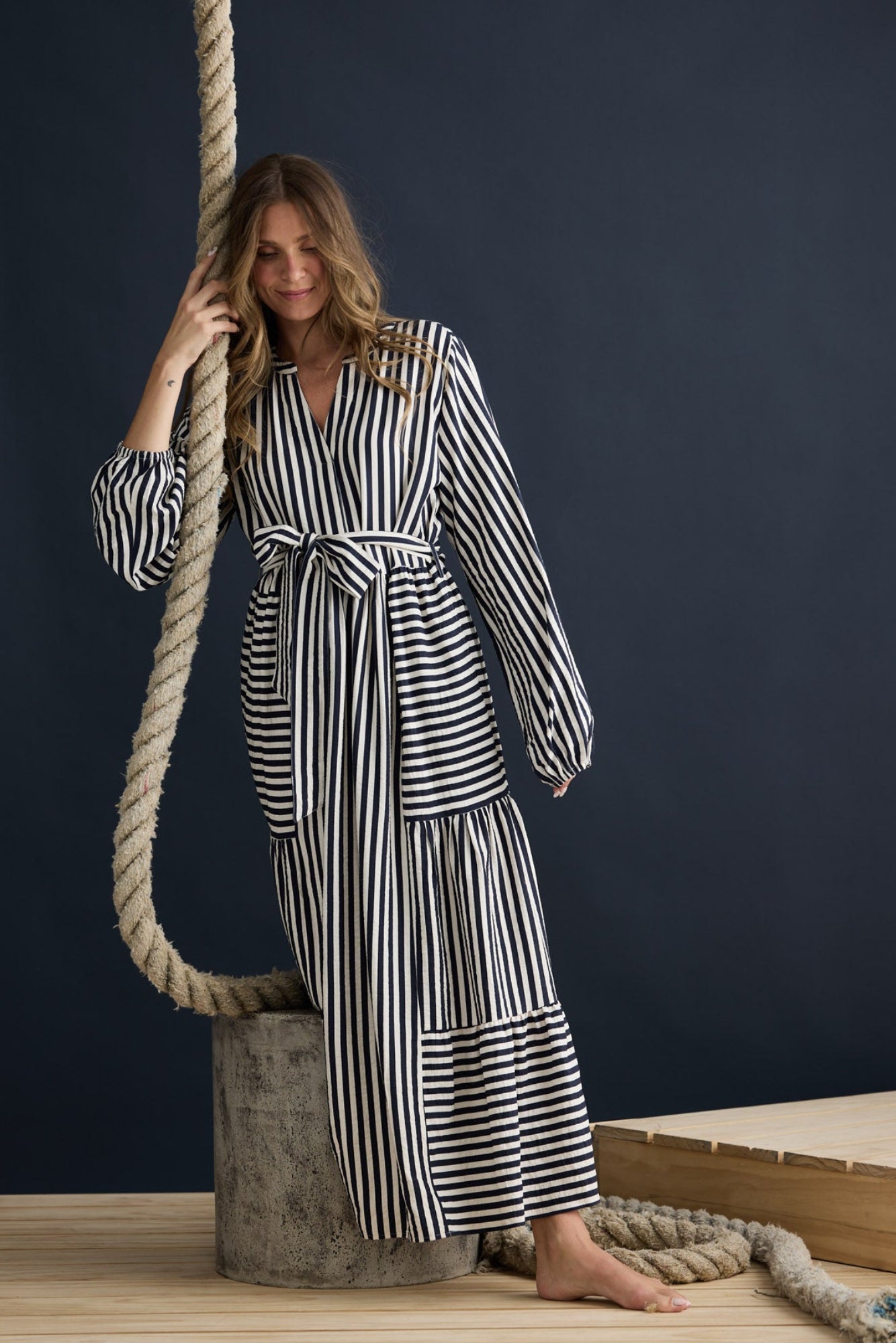 Model wearing Marla Dress Navy and White Stripe with balloon sleeves and waist tie, campaign lifestyle view