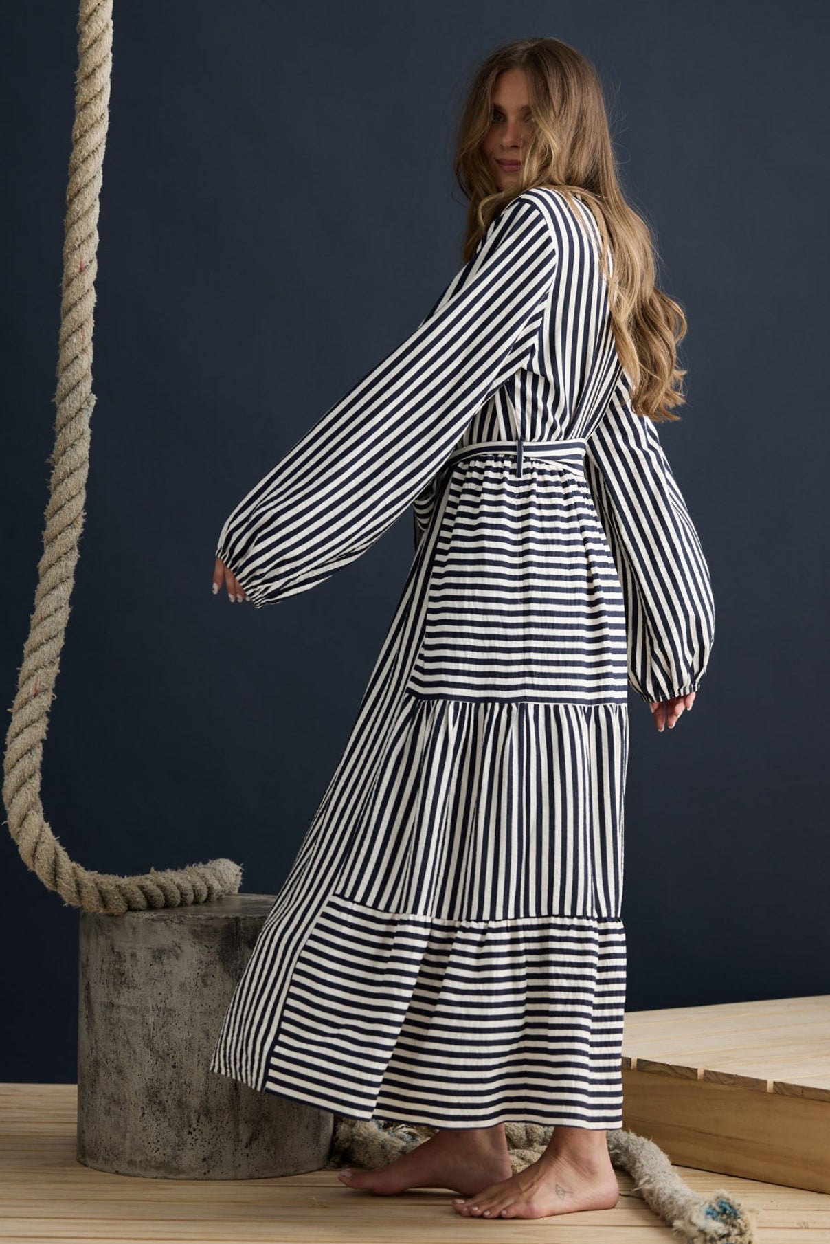 Model wearing Marla Dress Navy and White Stripe with balloon sleeves and waist tie, campaign lifestyle view