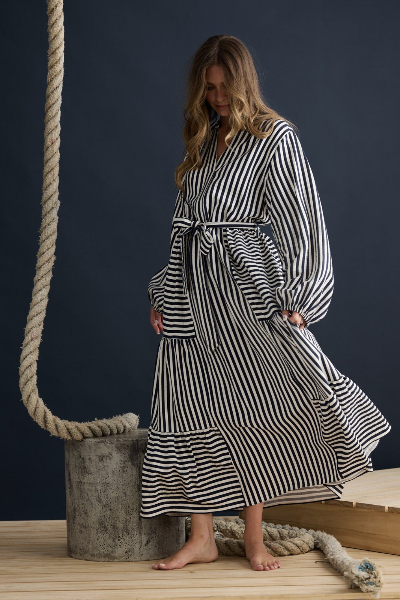 Model wearing Marla Dress Navy and White Stripe with balloon sleeves and waist tie, campaign lifestyle view