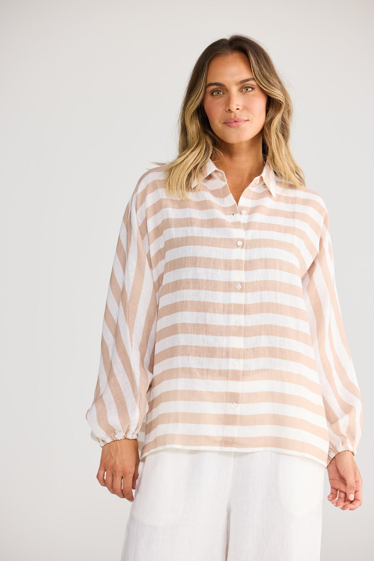 Model wearing Cliffside Shirt in natural with white, front view. Oversized button front, balloon sleeve, tan/white stripe.