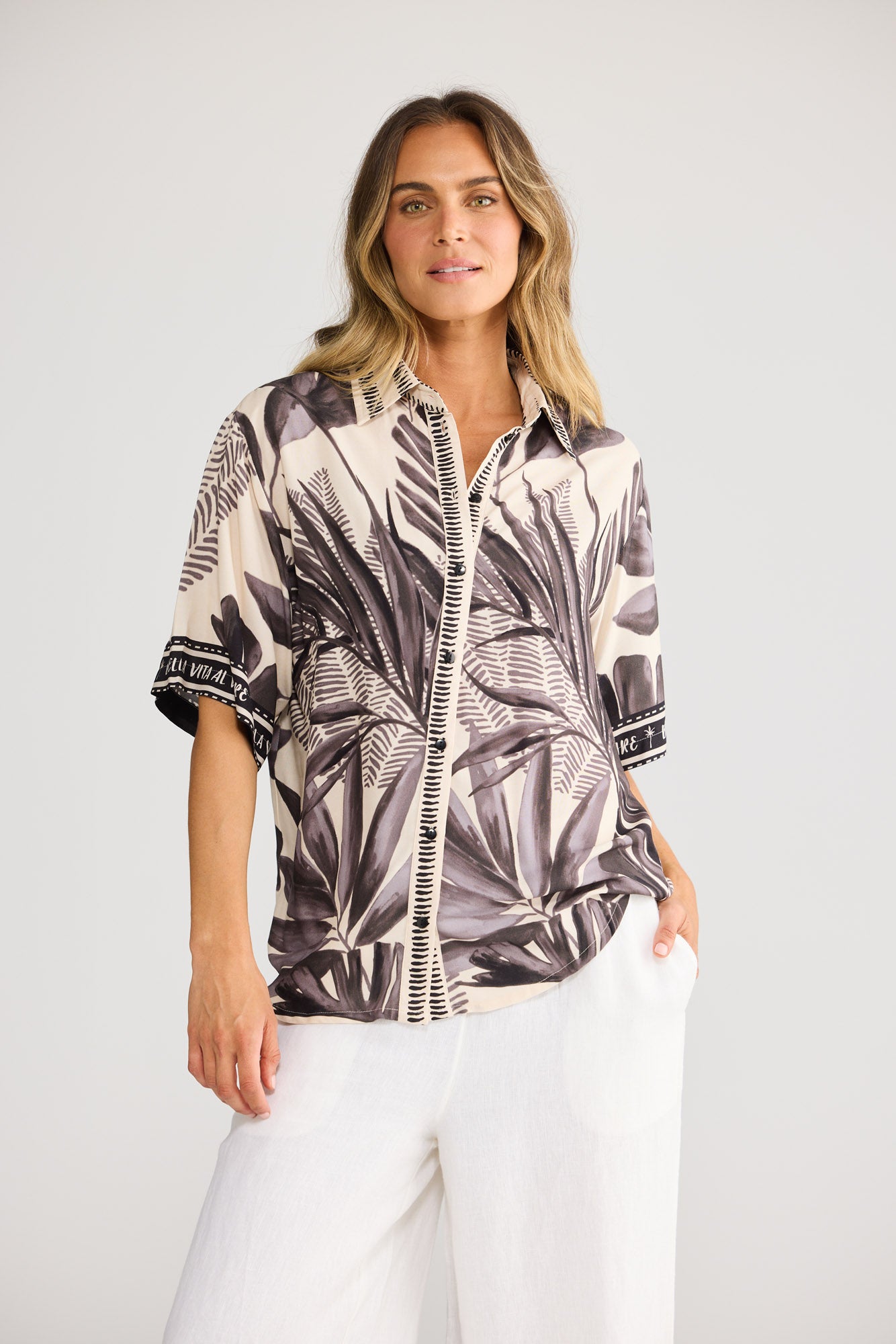 Model wearing Playa Shirt in sunset palm, front view. Relaxed short sleeve, button front, black-and-cream palm-leaf print.