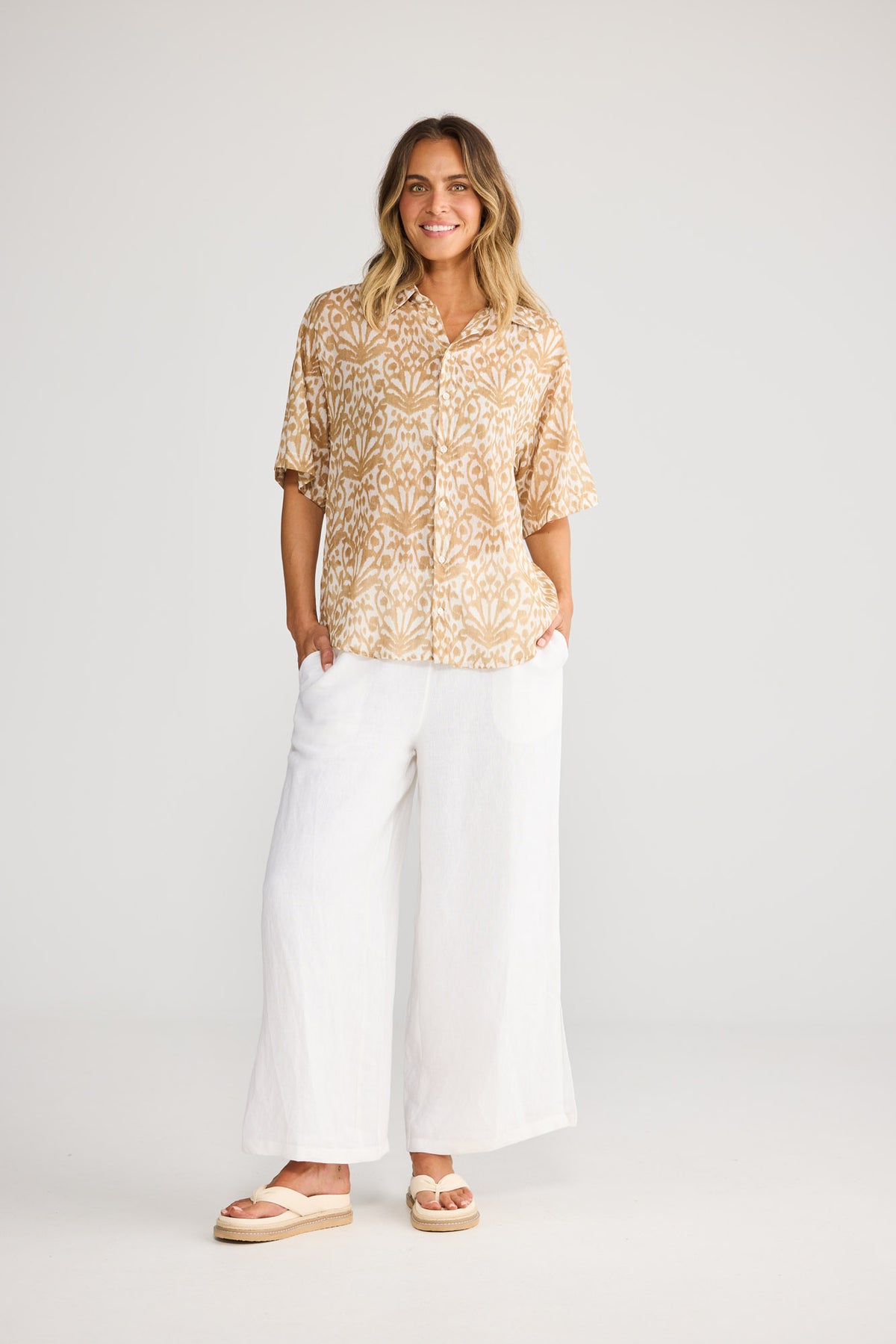 Model wearing Playa Shirt in taupe spring fan, front view. Relaxed short sleeve, button front, tan ikat fan print.