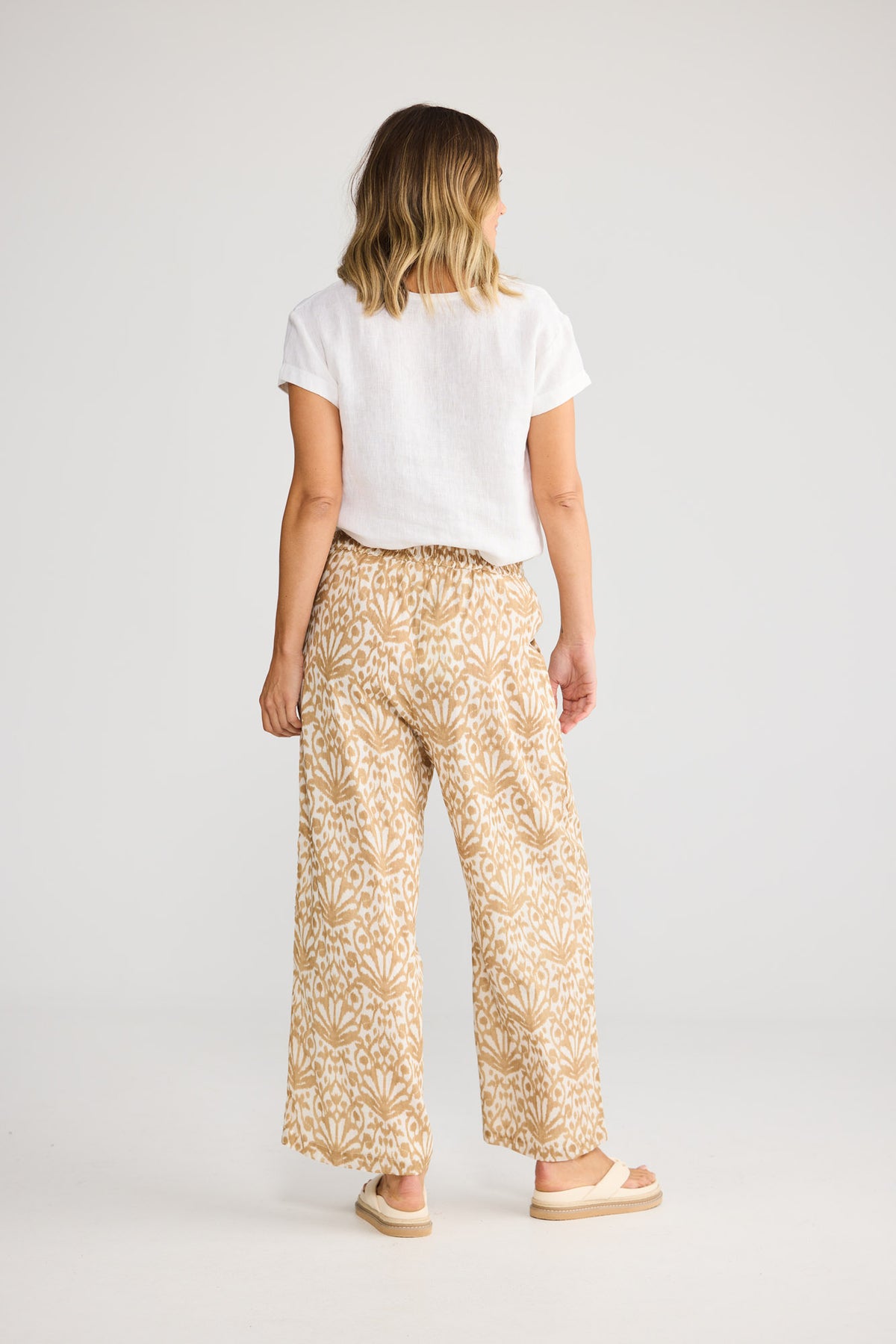 Model wearing Playa Pant in taupe spring fan, front view. Relaxed wide leg, elasticated waistband, tan ikat fan print.