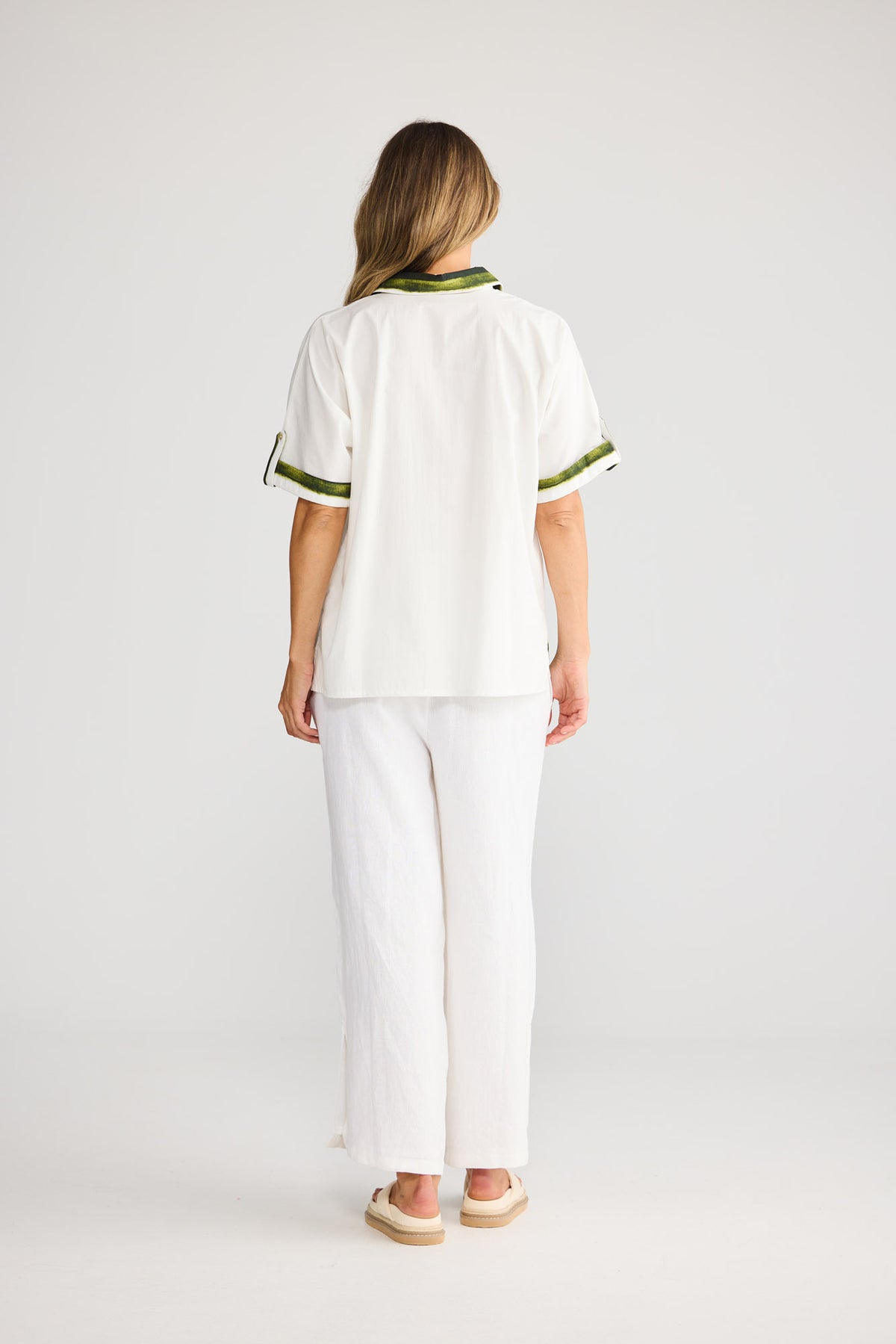 Model wearing Nalani Shirt in botanica print, front view. Relaxed button-front shirt, green tropical leaf print.