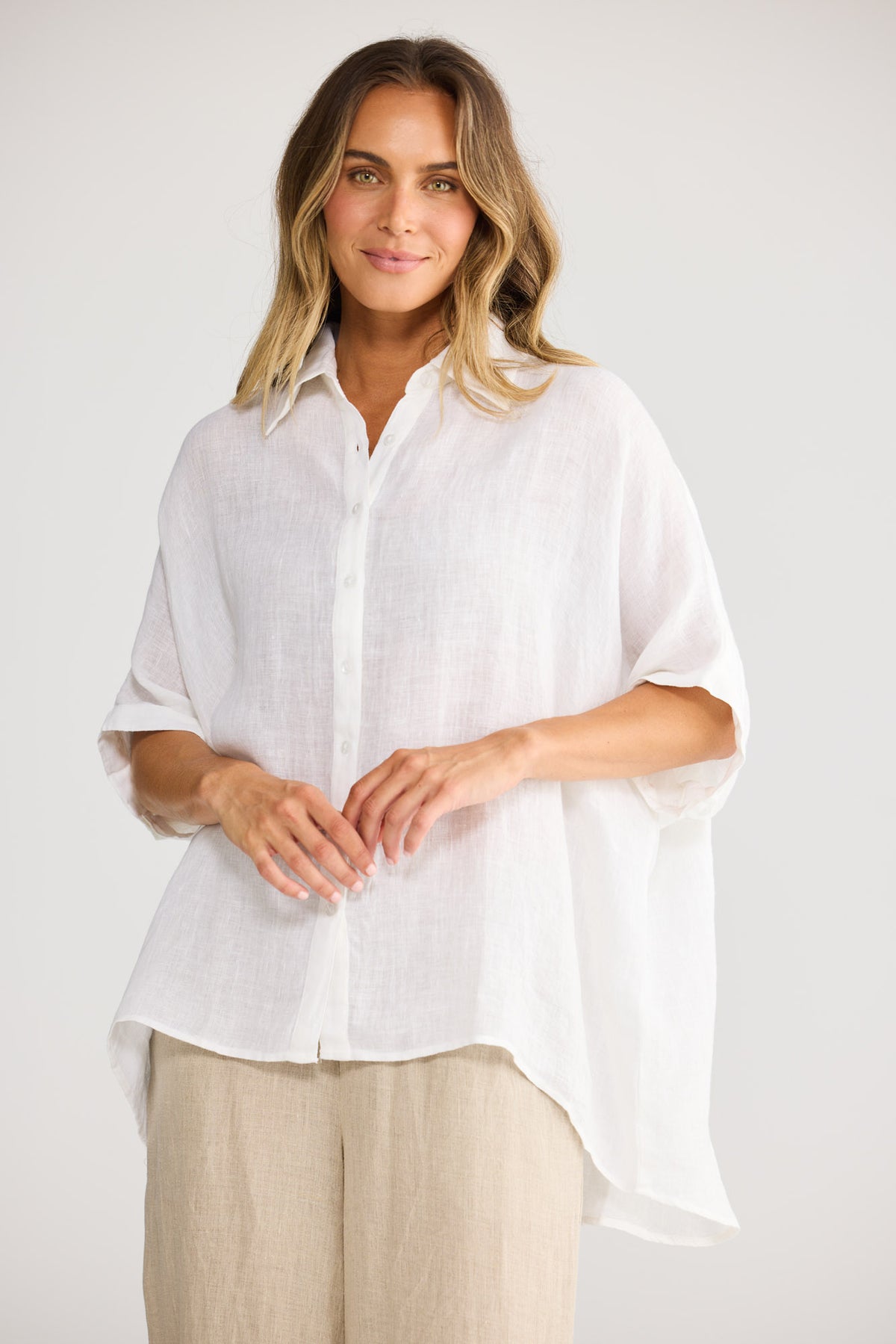 Model wearing Indigo Shirt in white, front view. Relaxed oversized fit, collared, rolled short sleeve cuff.