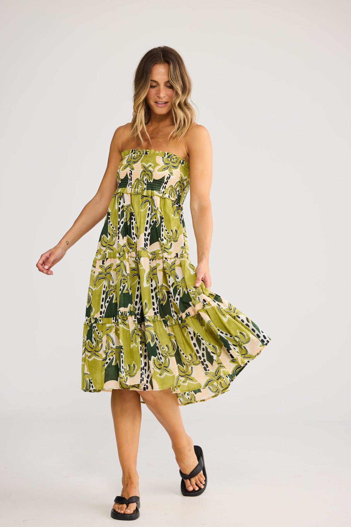 Model wearing Pier Skirt in tropical deco, front view. Shirred waist panel, tiered maxi with green banana-leaf stripe print.