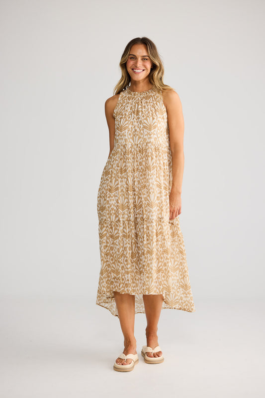 Model wearing Margot Dress in taupe spring fan, front view. Gathered halter, tiered hi-lo skirt, tan ikat fan print.