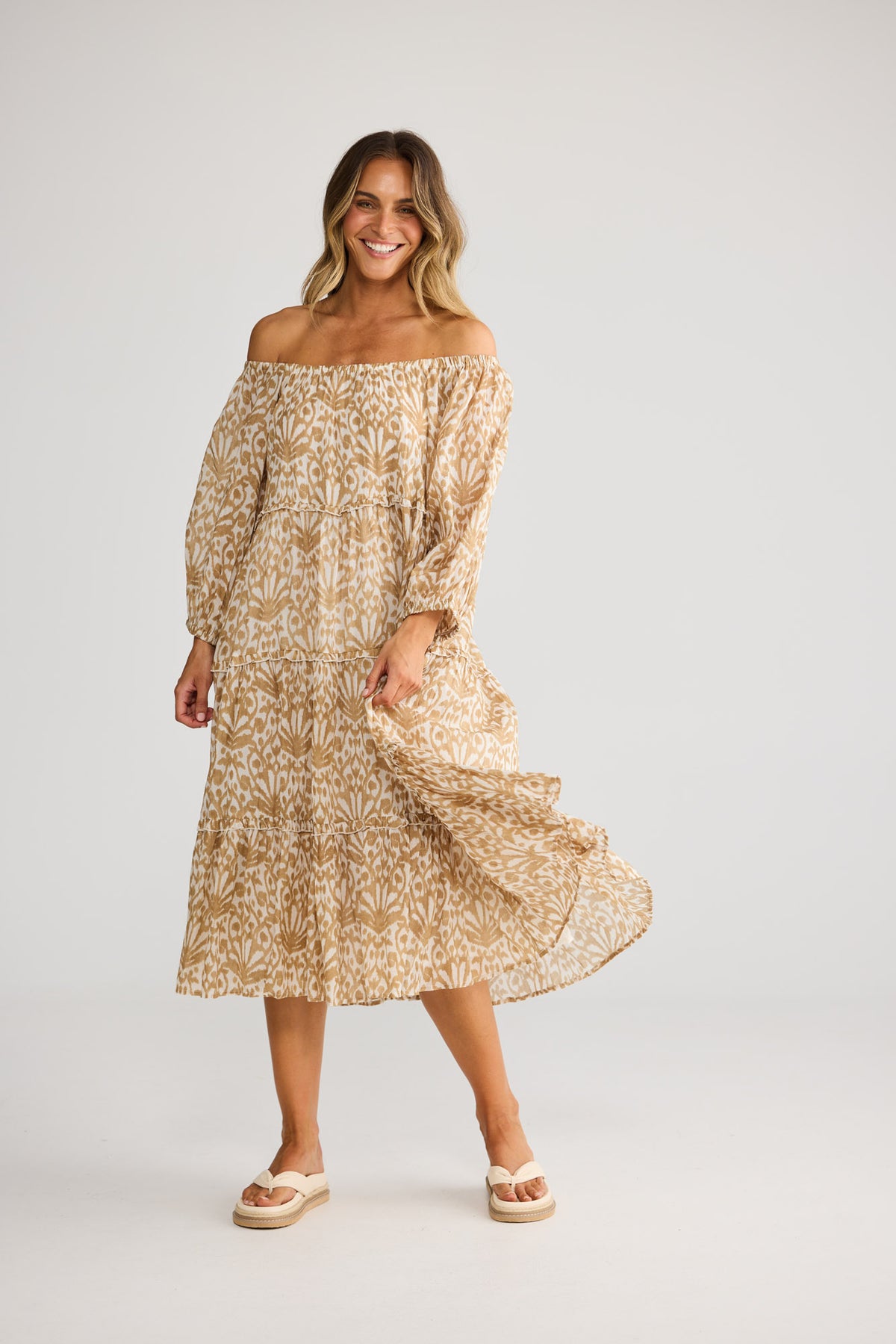 Model wearing Grenadine Dress in taupe spring fan, front view. Raglan sleeve, elasticated cuff, tiered skirt, ikat fan print.