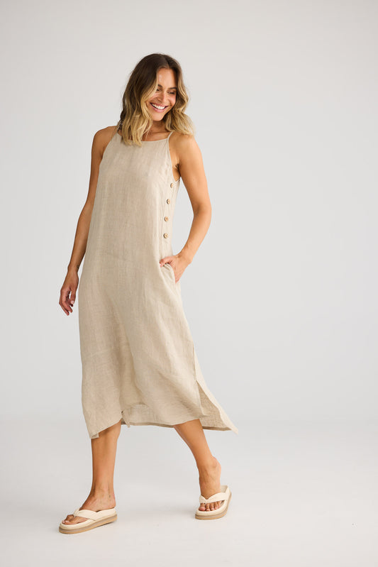 Model wearing Cliffside Maxi Dress in natural linen, front view. Spaghetti straps, button detail down one side seam.