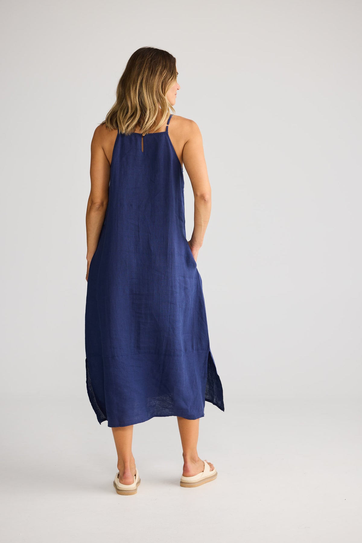 Model wearing Cliffside Maxi Dress in navy, front view. Spaghetti straps, button detail down one side seam.