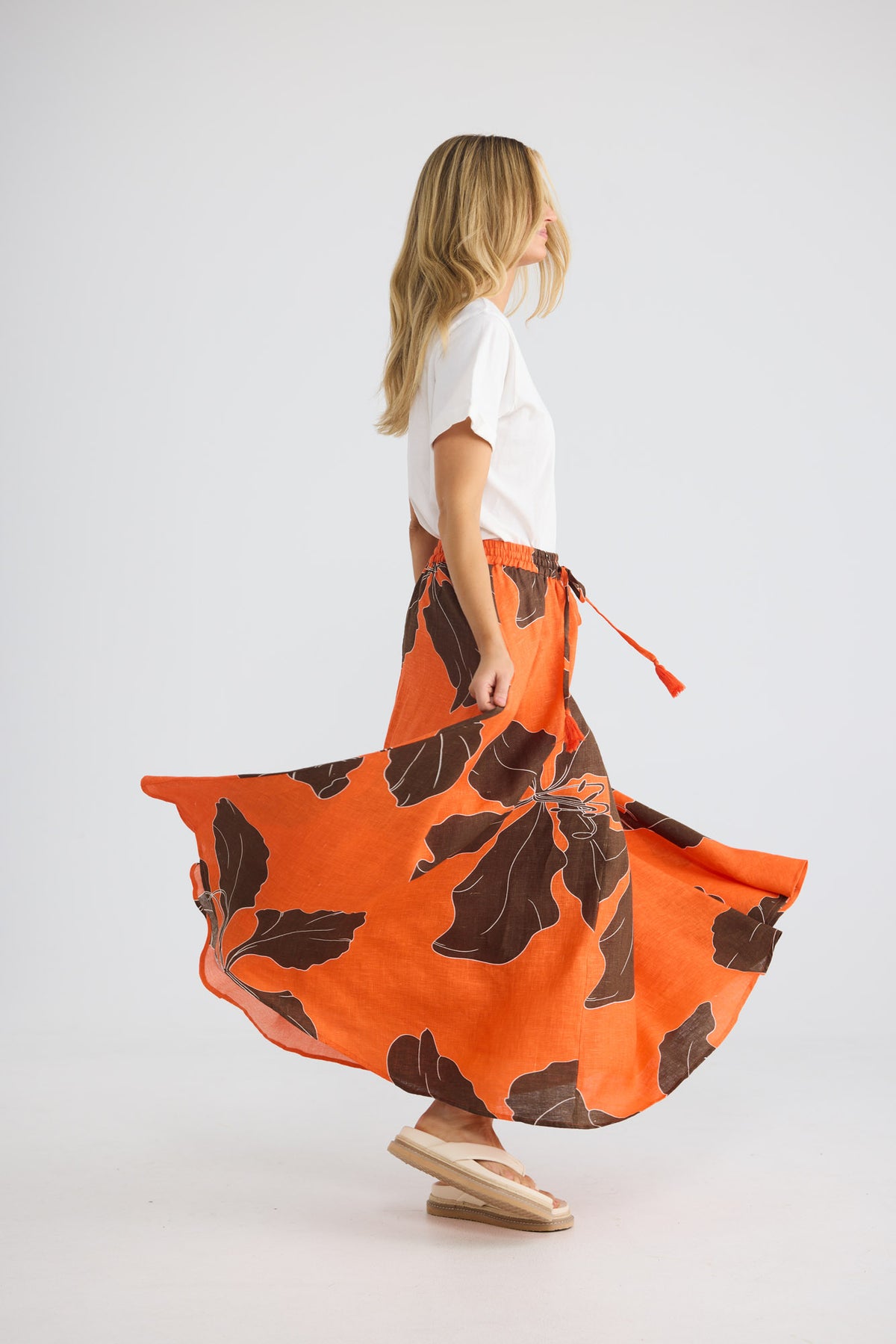 Model wearing Carousel Skirt in hibiscus breeze, front view. Elasticated drawstring waist, maxi silhouette, large leaf print.