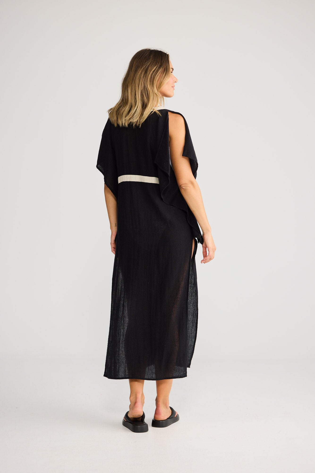 Model wearing Luma Kaftan in black with natural, front view. Dolman sleeve, V-neck with natural trim, side split.