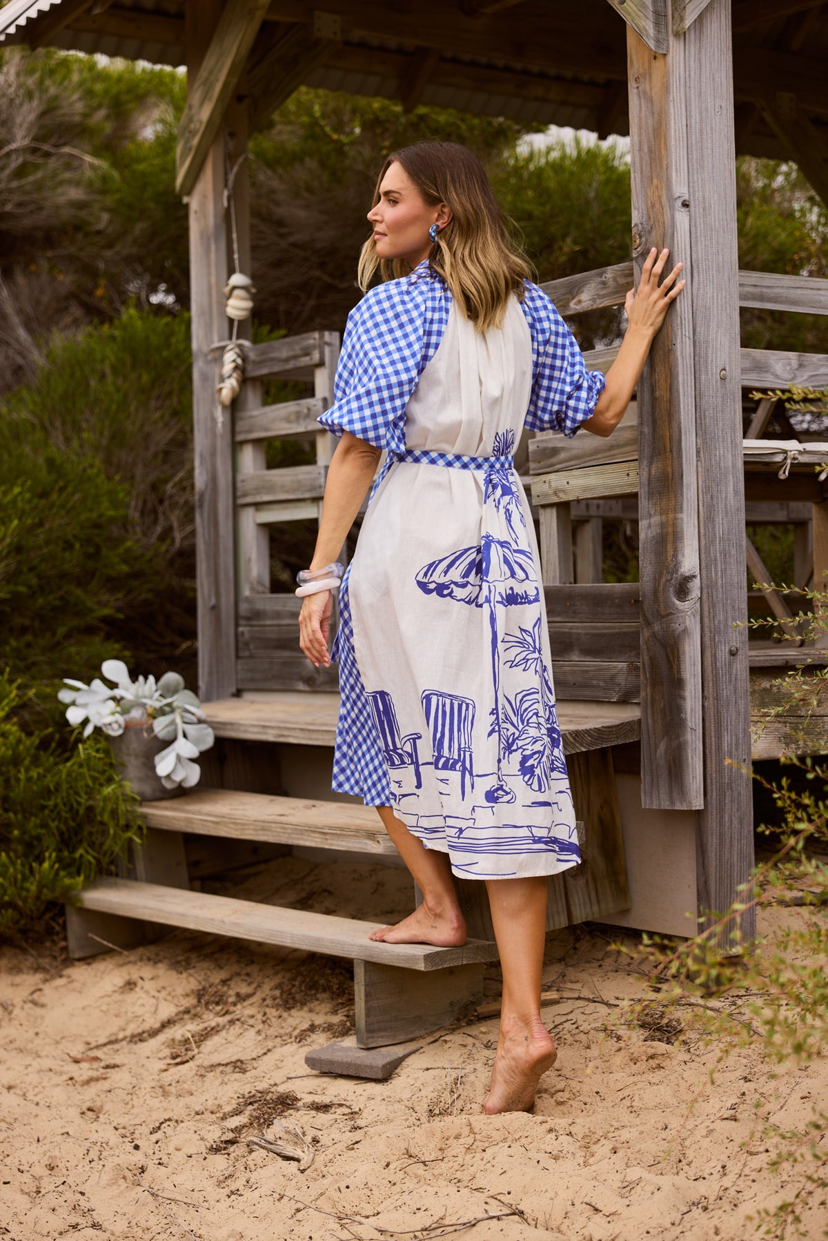 Model wearing Somara Dress in blue check, front view. Collared shirt dress, balloon sleeve, tie waist, gingham check.