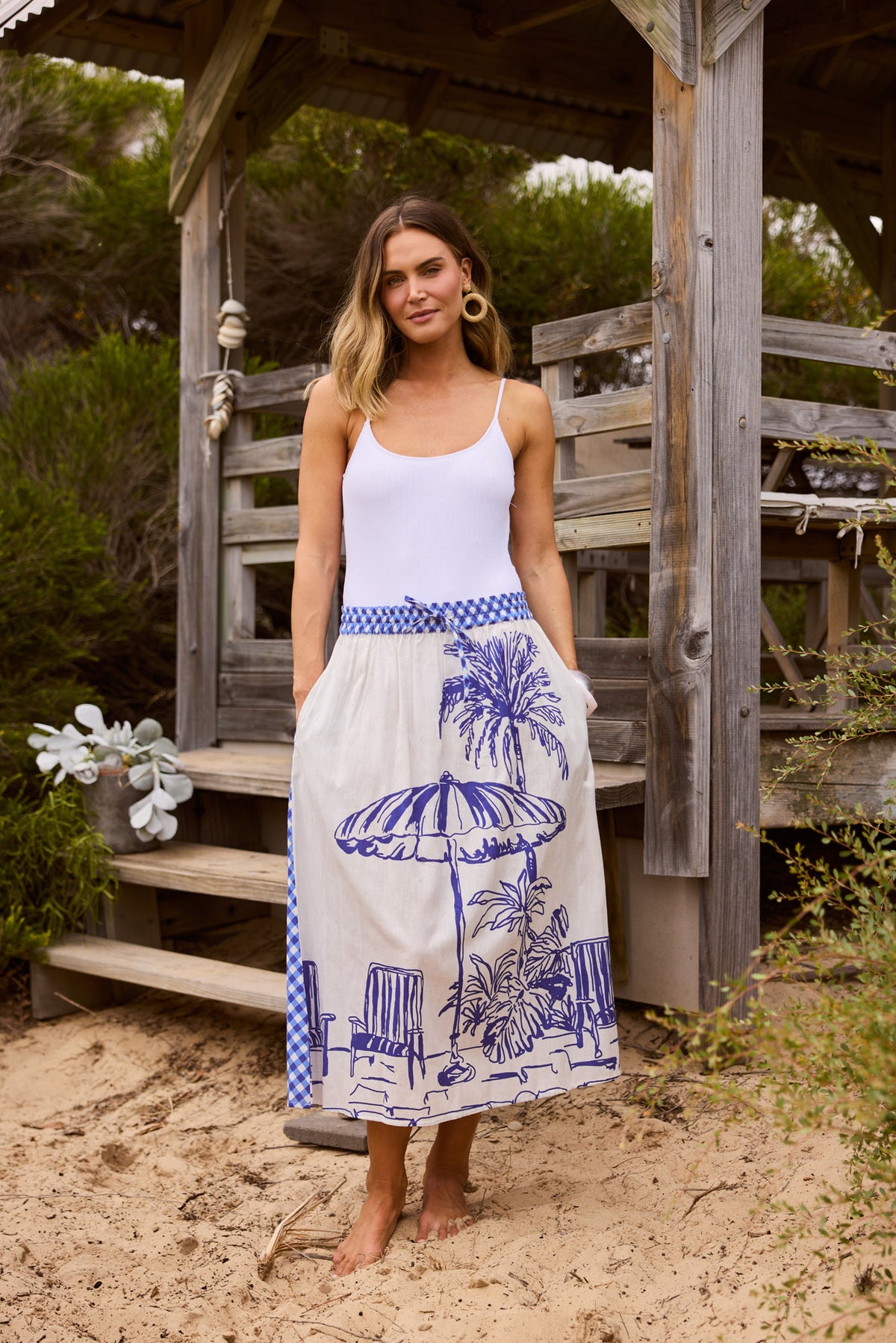 Model wearing Somara Skirt, close front view. A-line midi, cream ground with blue linework villa scenic print.