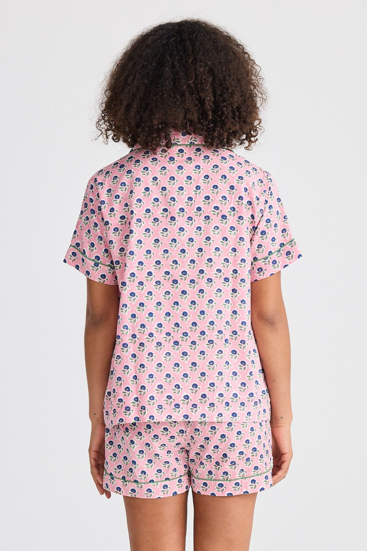 Person wearing a pink patterned pajama set on a white background