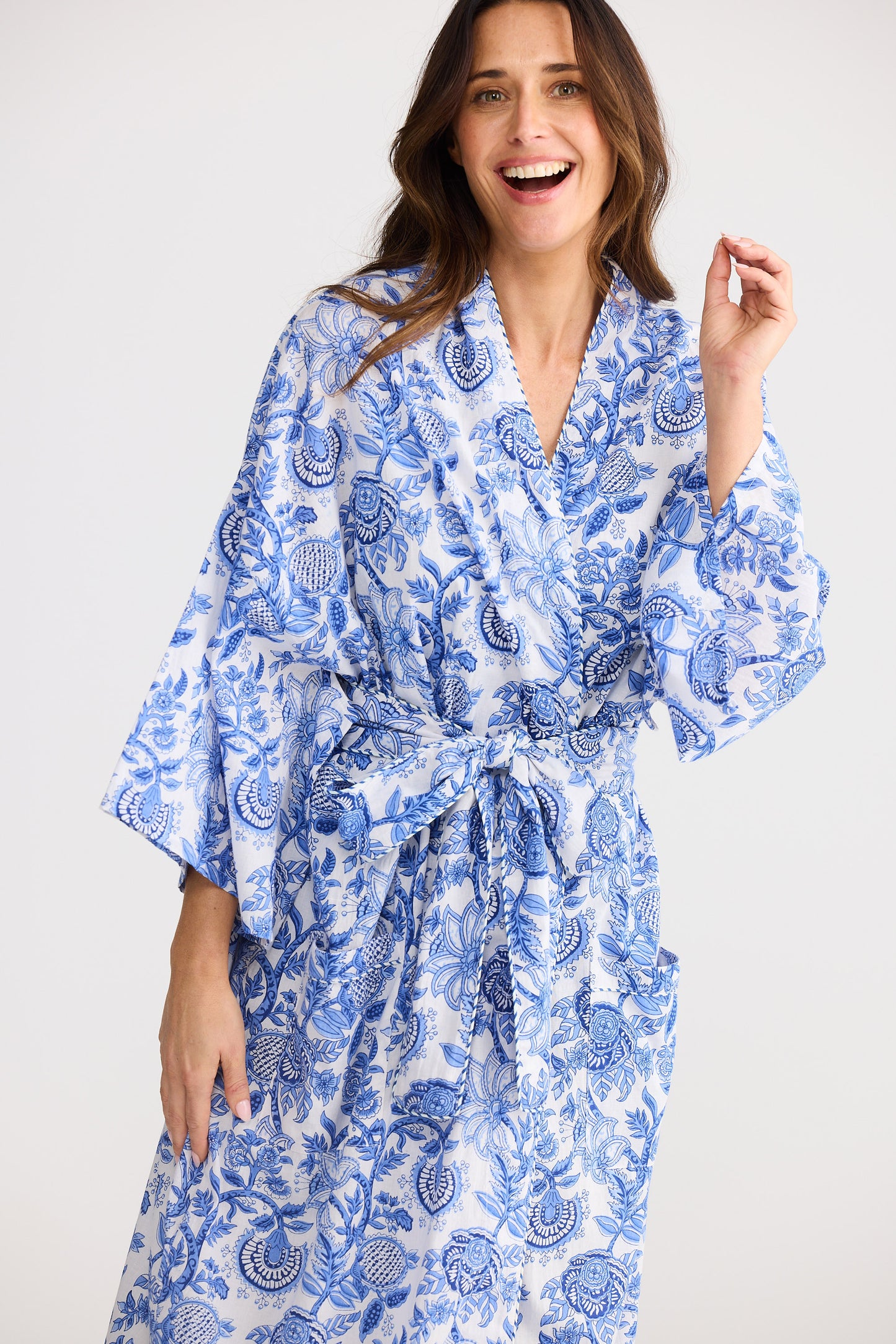 Woman wearing a blue and white patterned robe against a plain background
