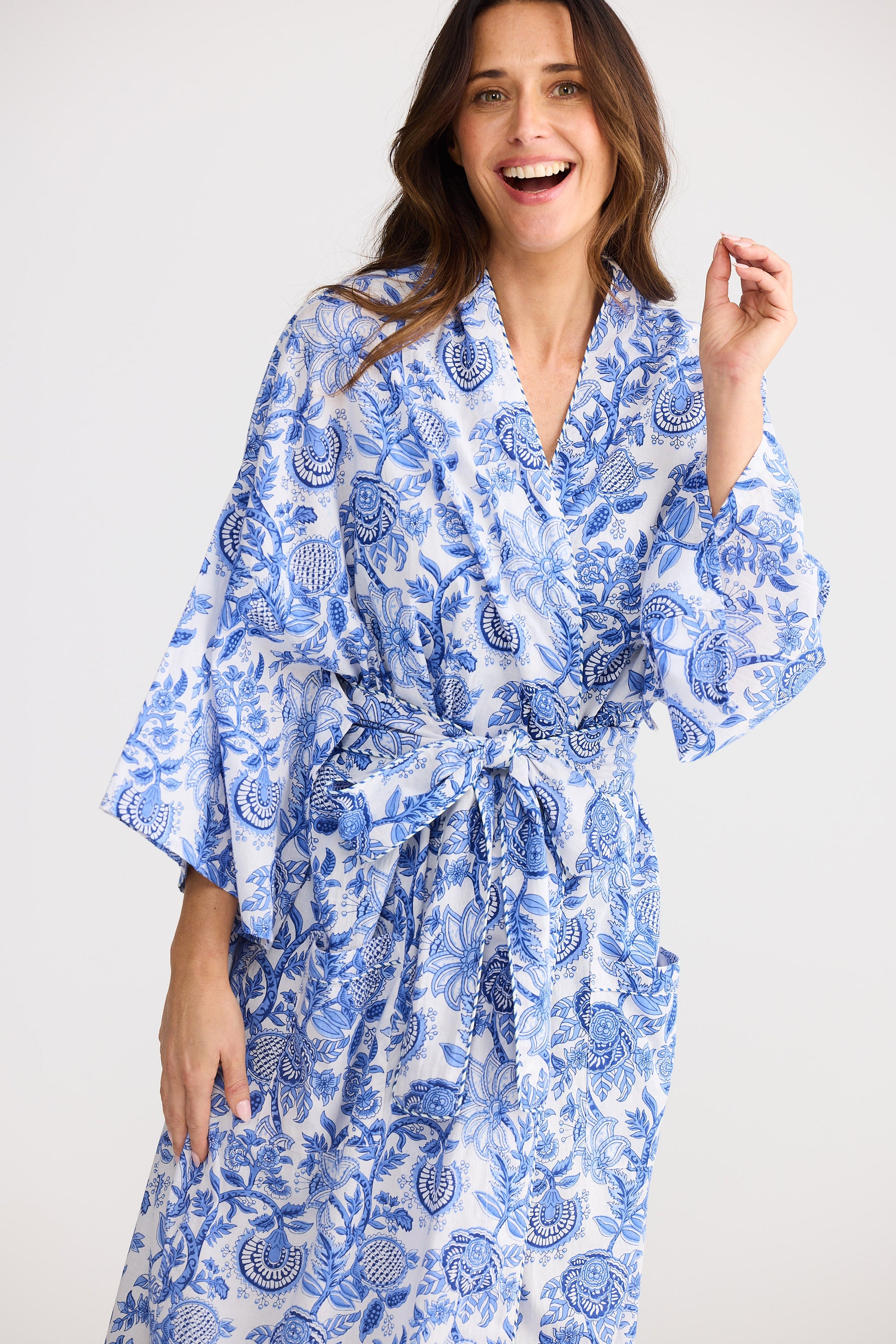 Woman wearing a blue and white patterned robe against a plain background