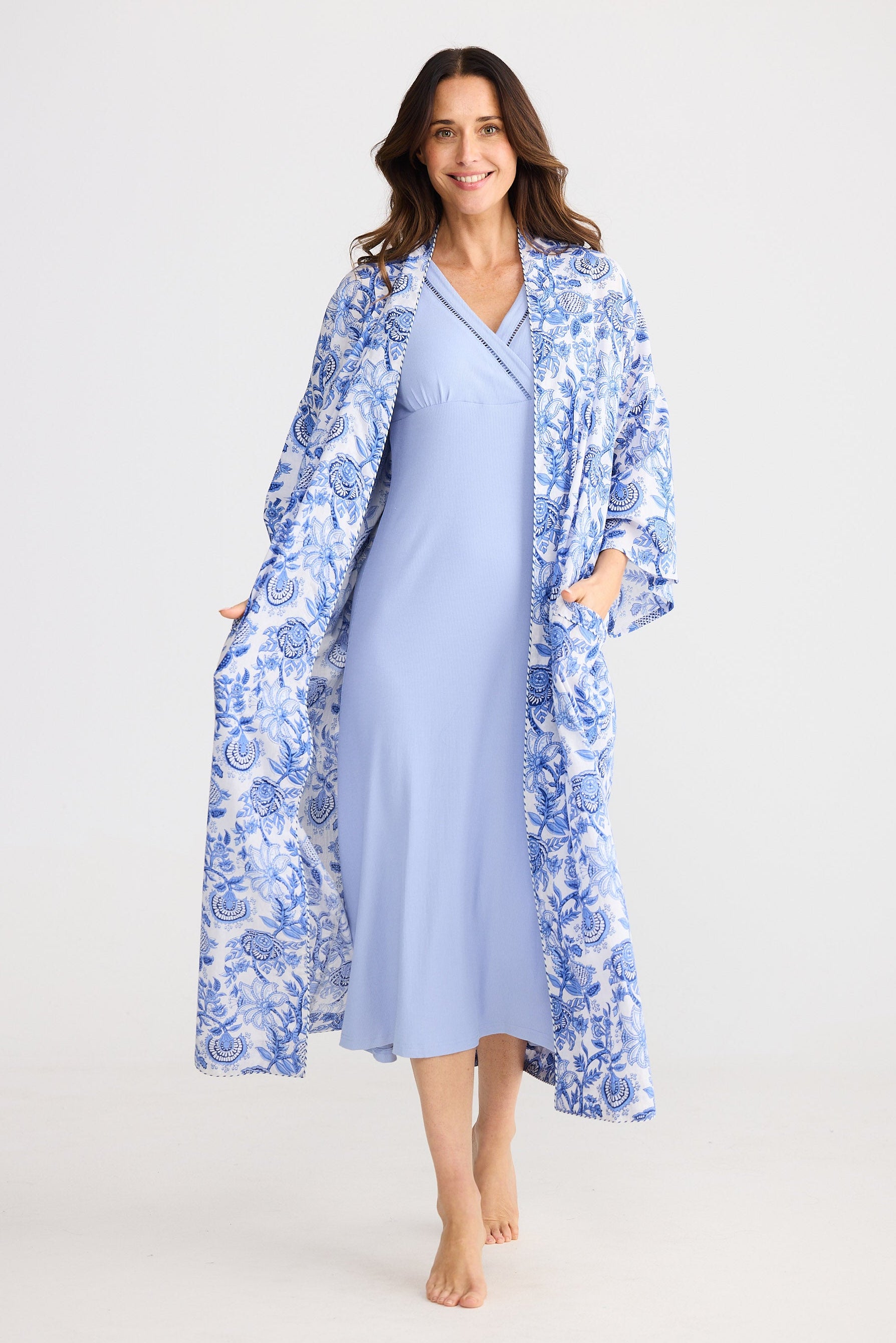 Woman wearing a blue floral robe over a light blue dress on a white background
