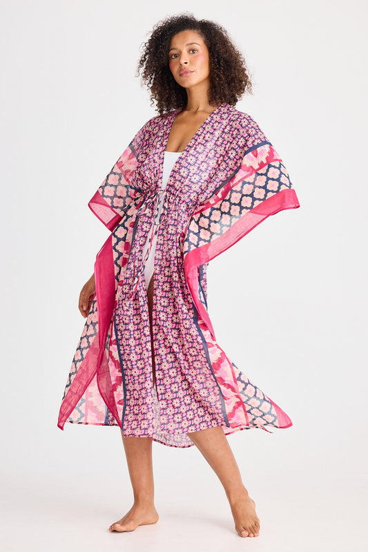 Woman wearing a pink and purple patterned kimono-style garment on a white background