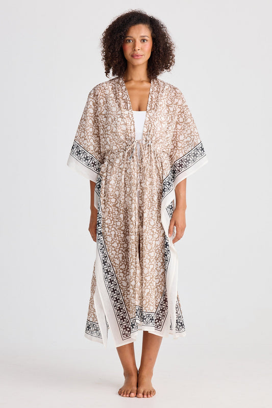 Woman wearing a beige and black patterned kaftan on a white background