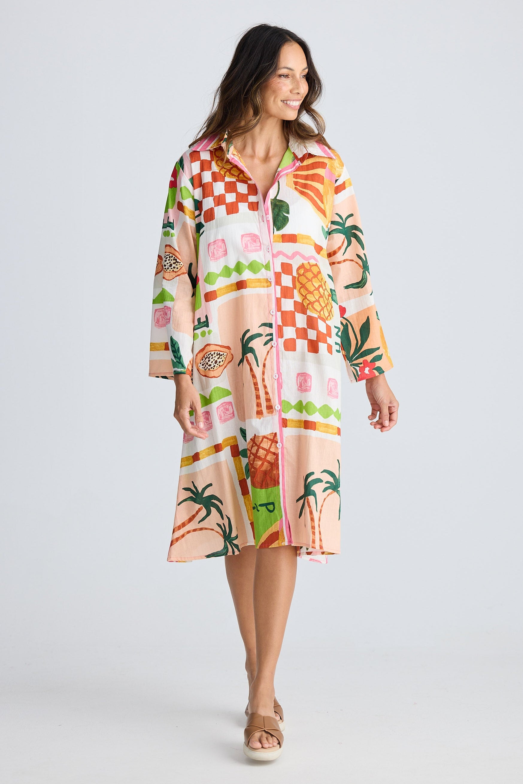 Woman wearing a colorful dress with fruit pattern on a white background