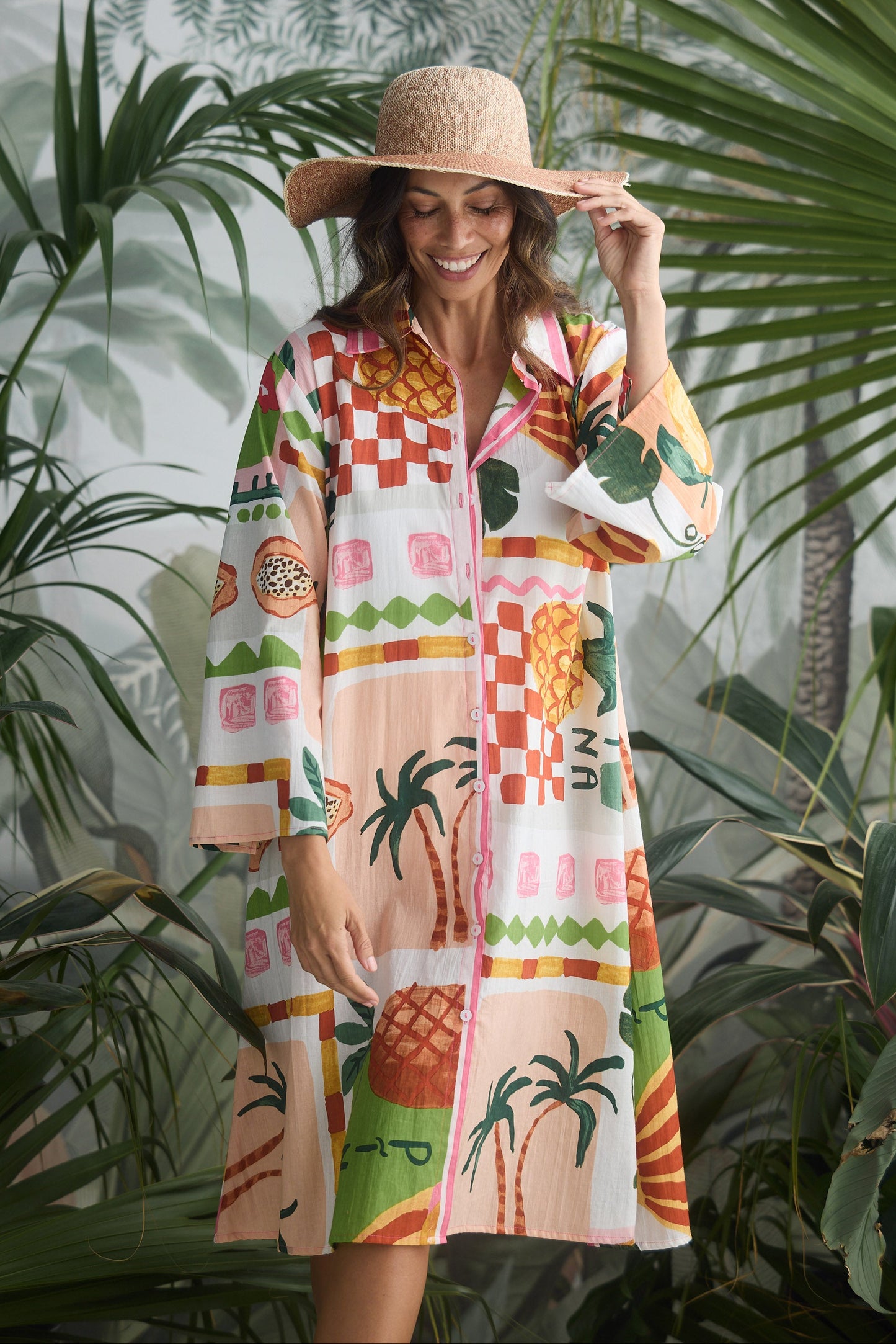 Woman wearing a colorful patterned dress and hat in a tropical setting