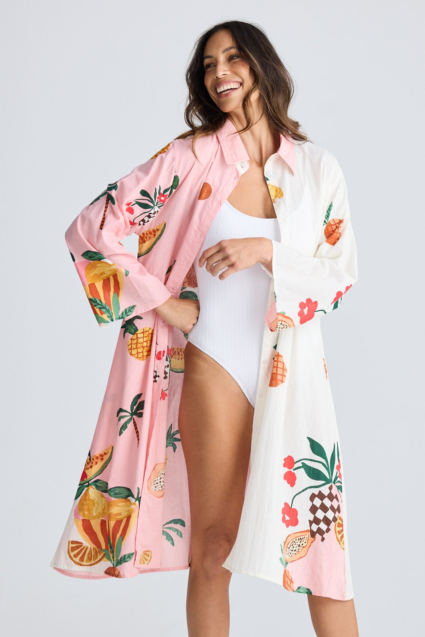 Woman wearing a pink floral kimono over a white outfit on a light gray background