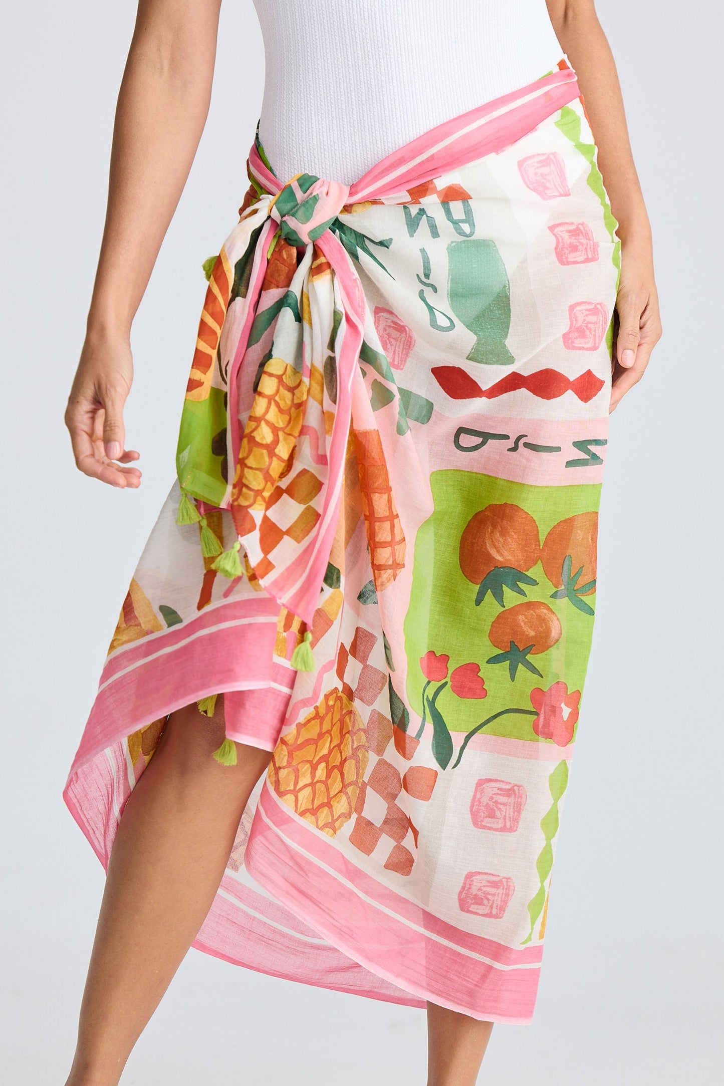 Person wearing a colorful fruit patterned sarong on a white background