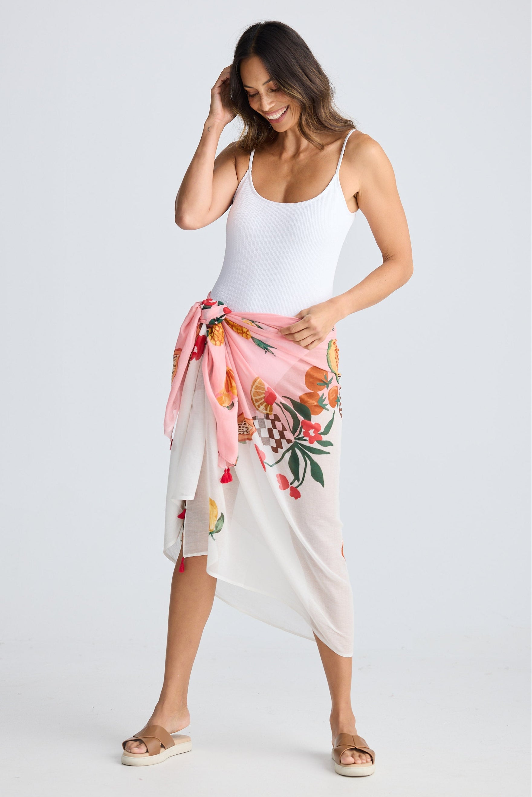 Woman wearing a white swimsuit with a colorful floral sarong on a white background