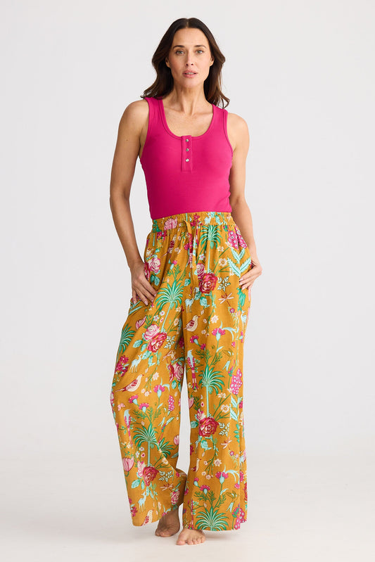 Woman wearing a pink top and yellow floral pants on a white background