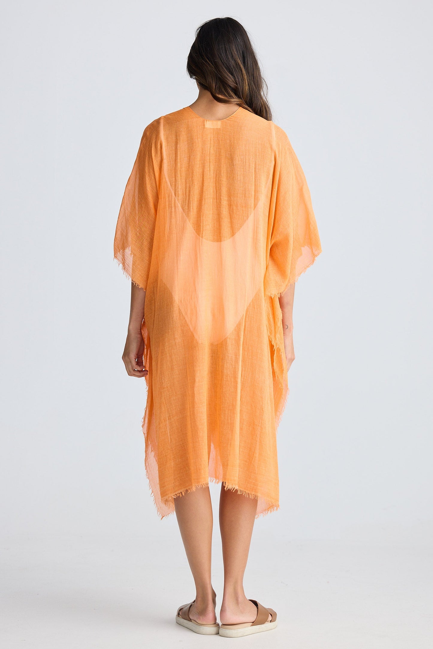 Woman wearing an orange cover-up against a white background
