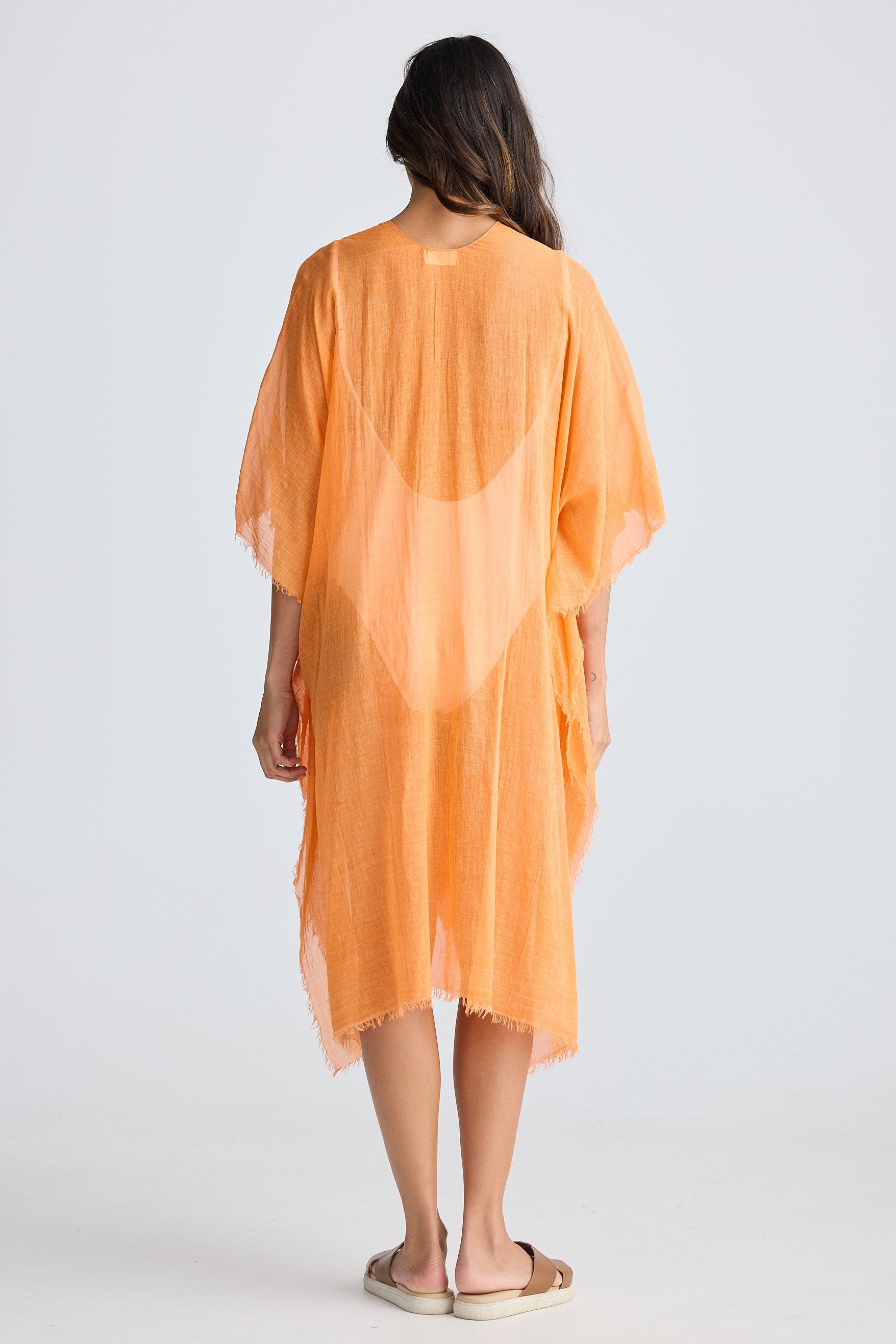 Woman wearing an orange cover-up against a white background