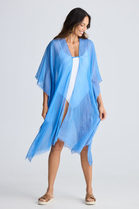 Woman wearing a light blue kimono-style garment over a white dress on a plain background